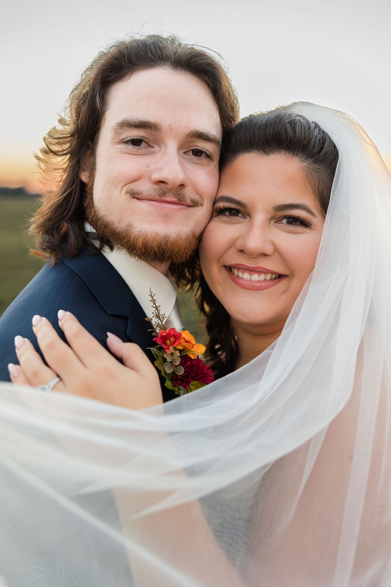 A romantic wedding portrait shows a couple sharing a tender moment with a flowing veil.