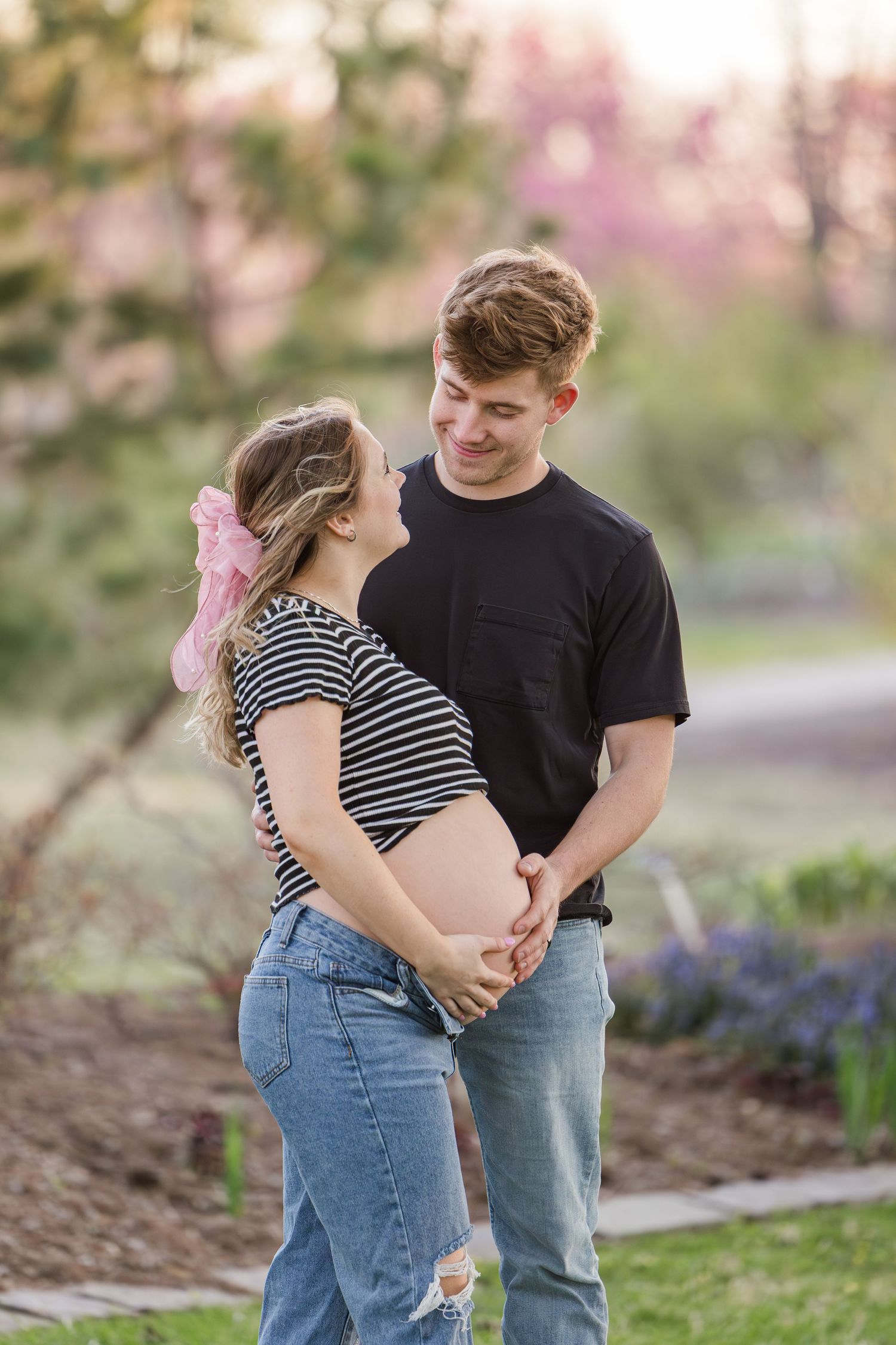 A couple shares an intimate moment among spring blossoms in a garden setting.