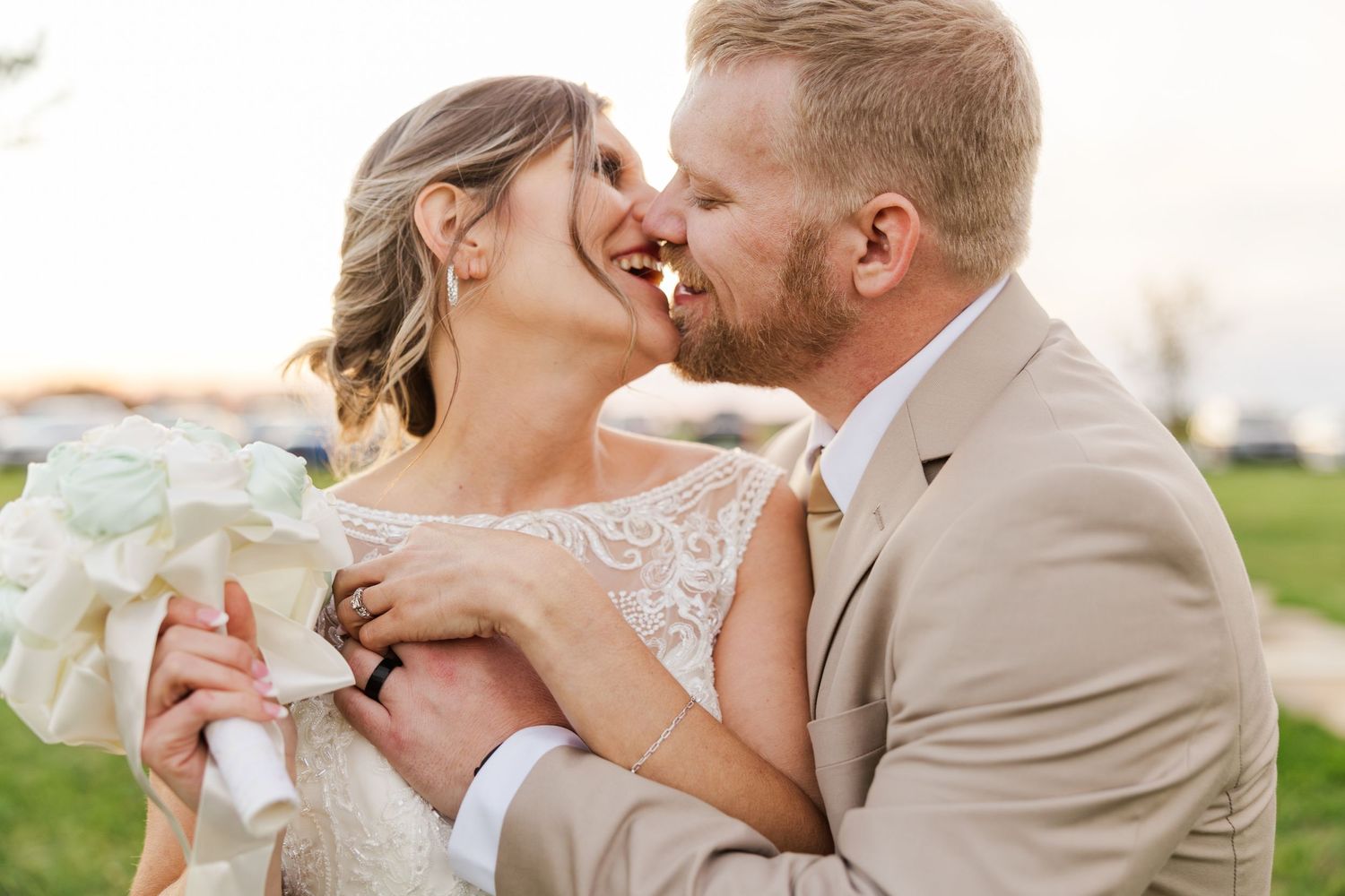 Romantic outdoor wedding moment with bride and groom in beige and white attire.