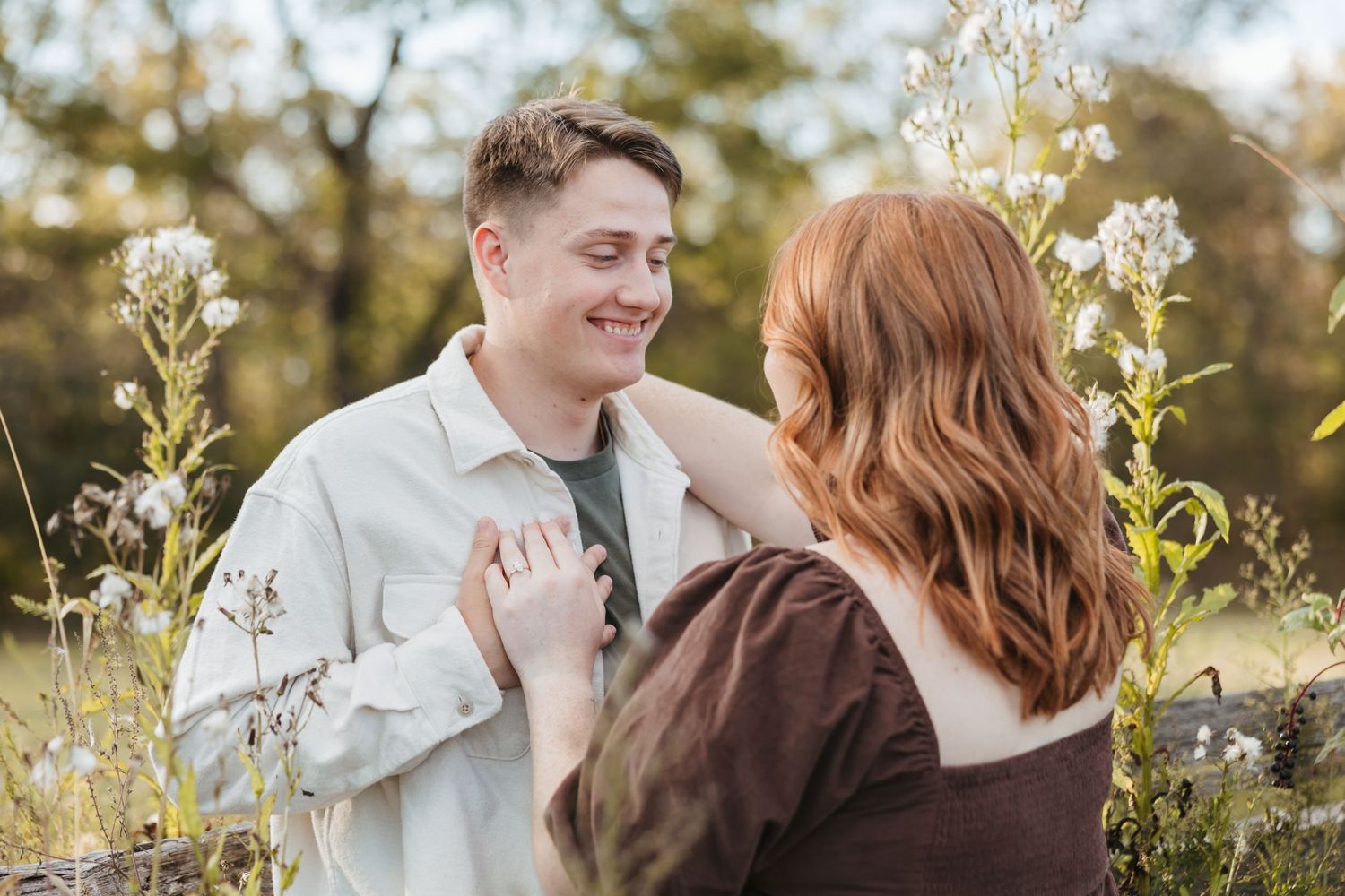 Happy couple sharing romantic moment among blooming wildflowers in natural light.