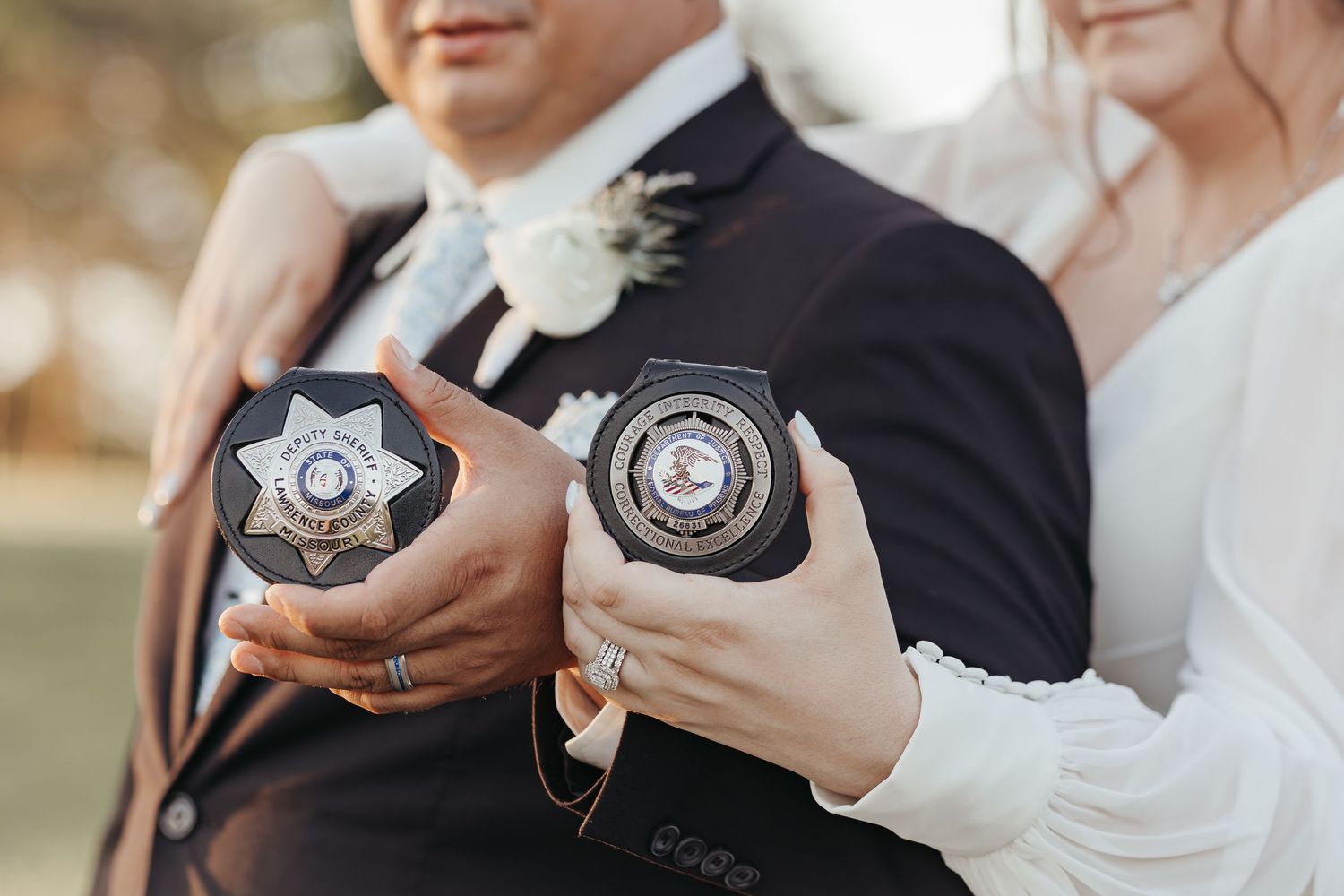 Close-up of hands holding police badges during wedding photo session.