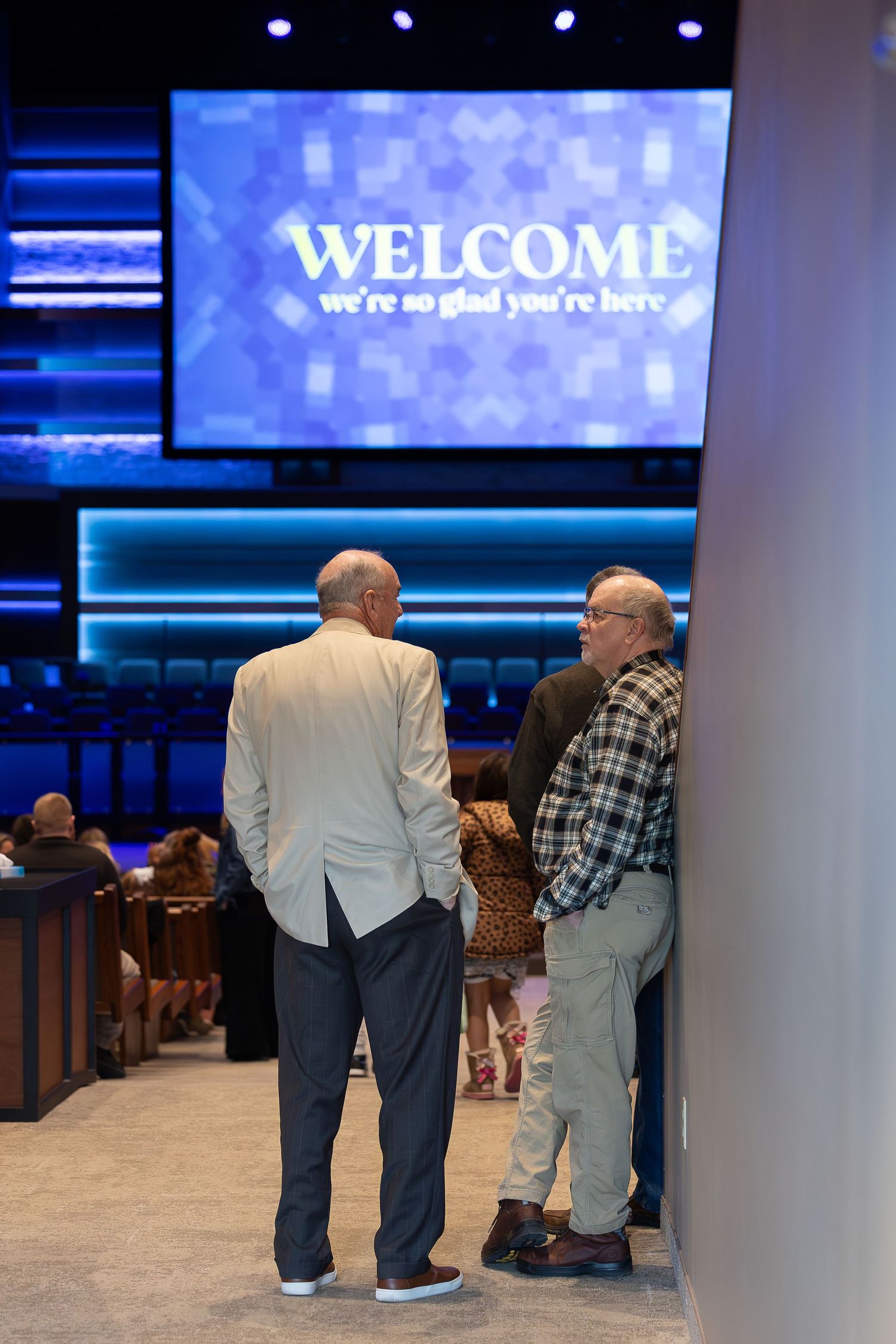 Two people conversing beneath a welcome sign in a church sanctuary.