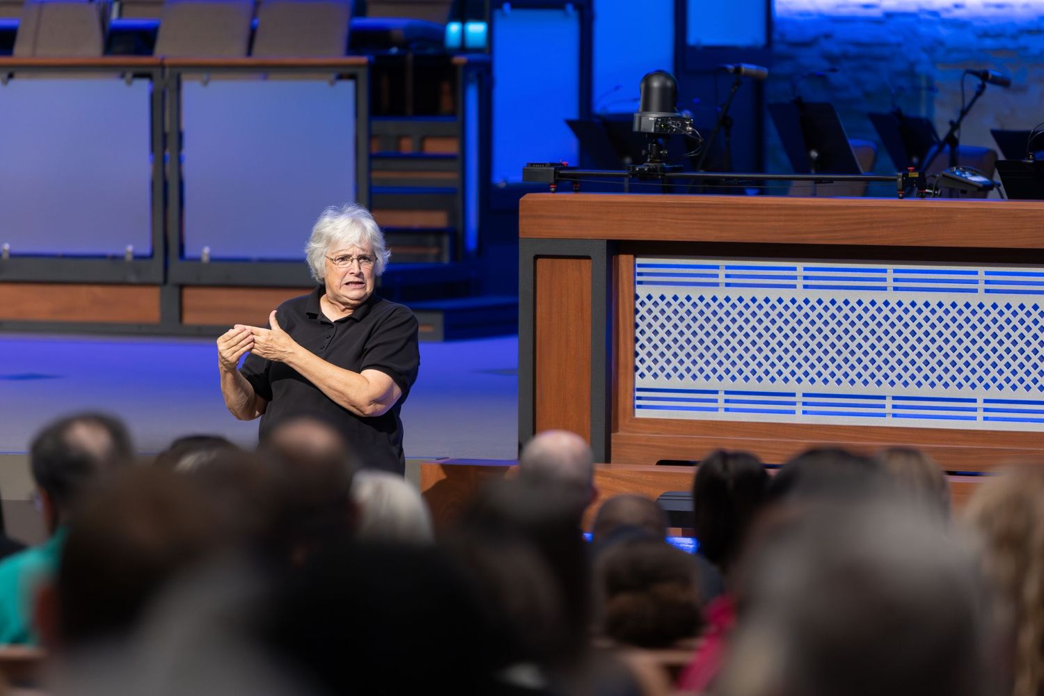 A presenter gestures while speaking to the congregation from the church platform.