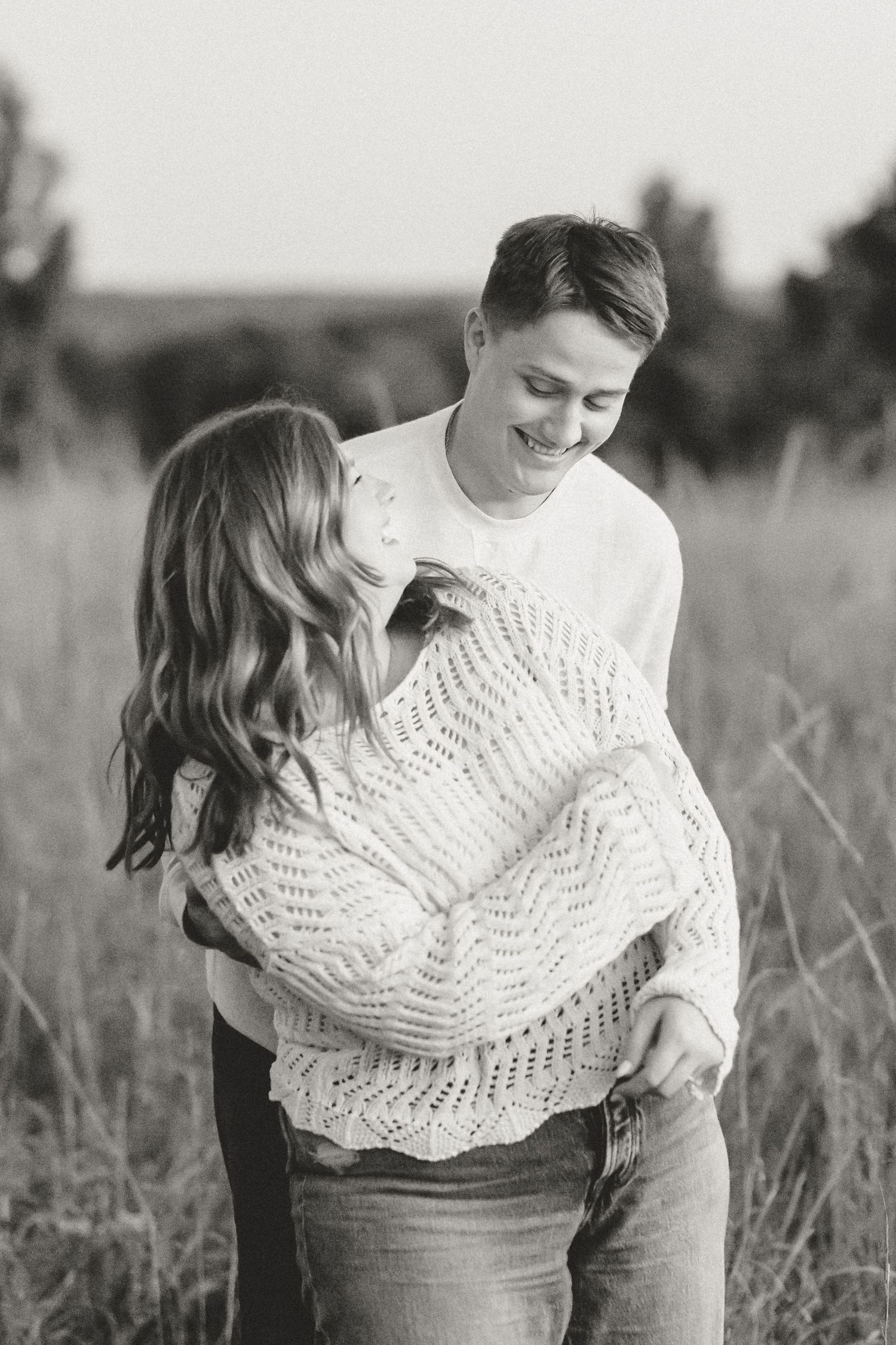 A romantic black and white portrait of a couple sharing an intimate moment outdoors.
