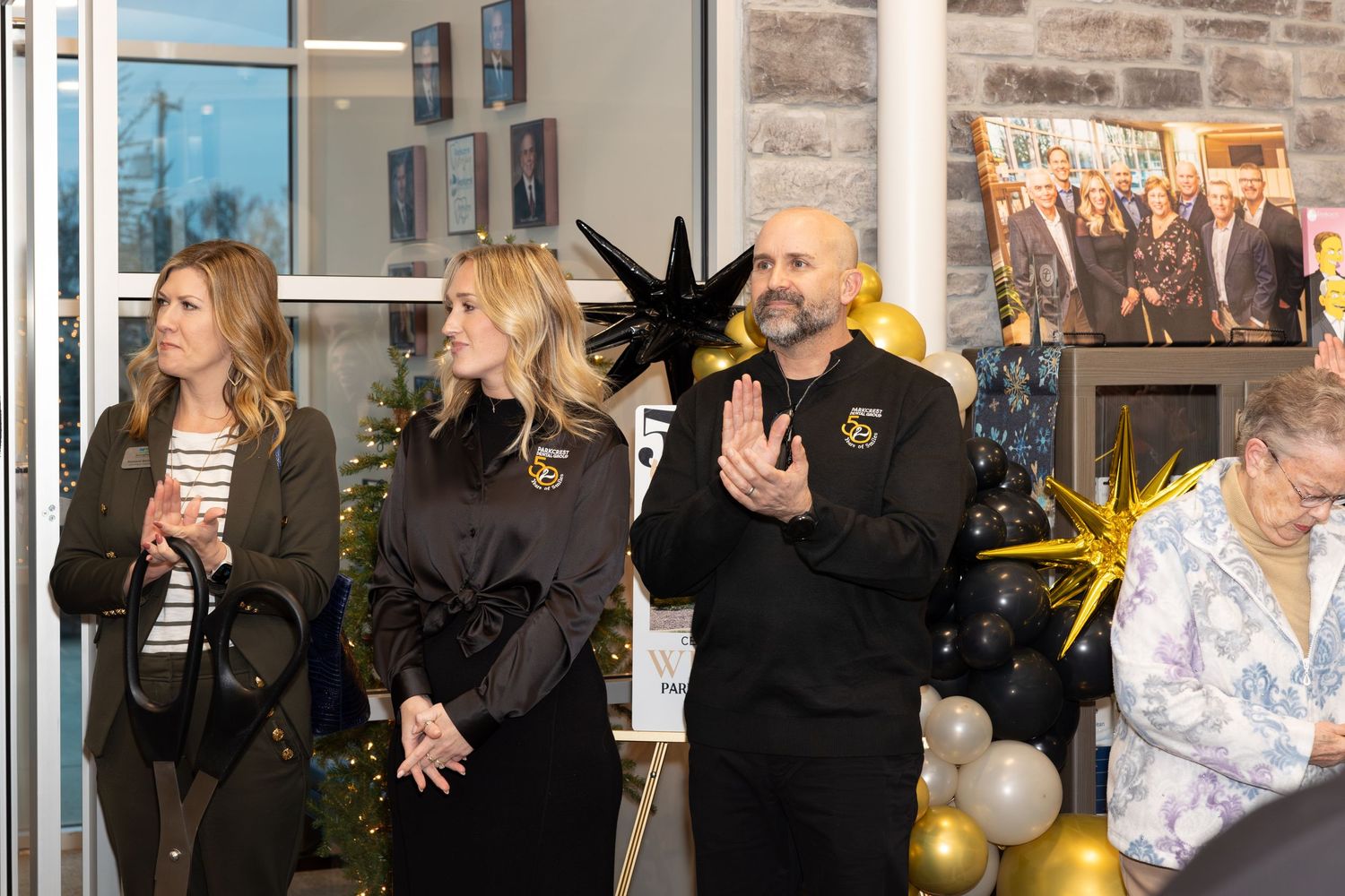 Staff members gather at an office celebration event decorated with balloons and stone wall decor.