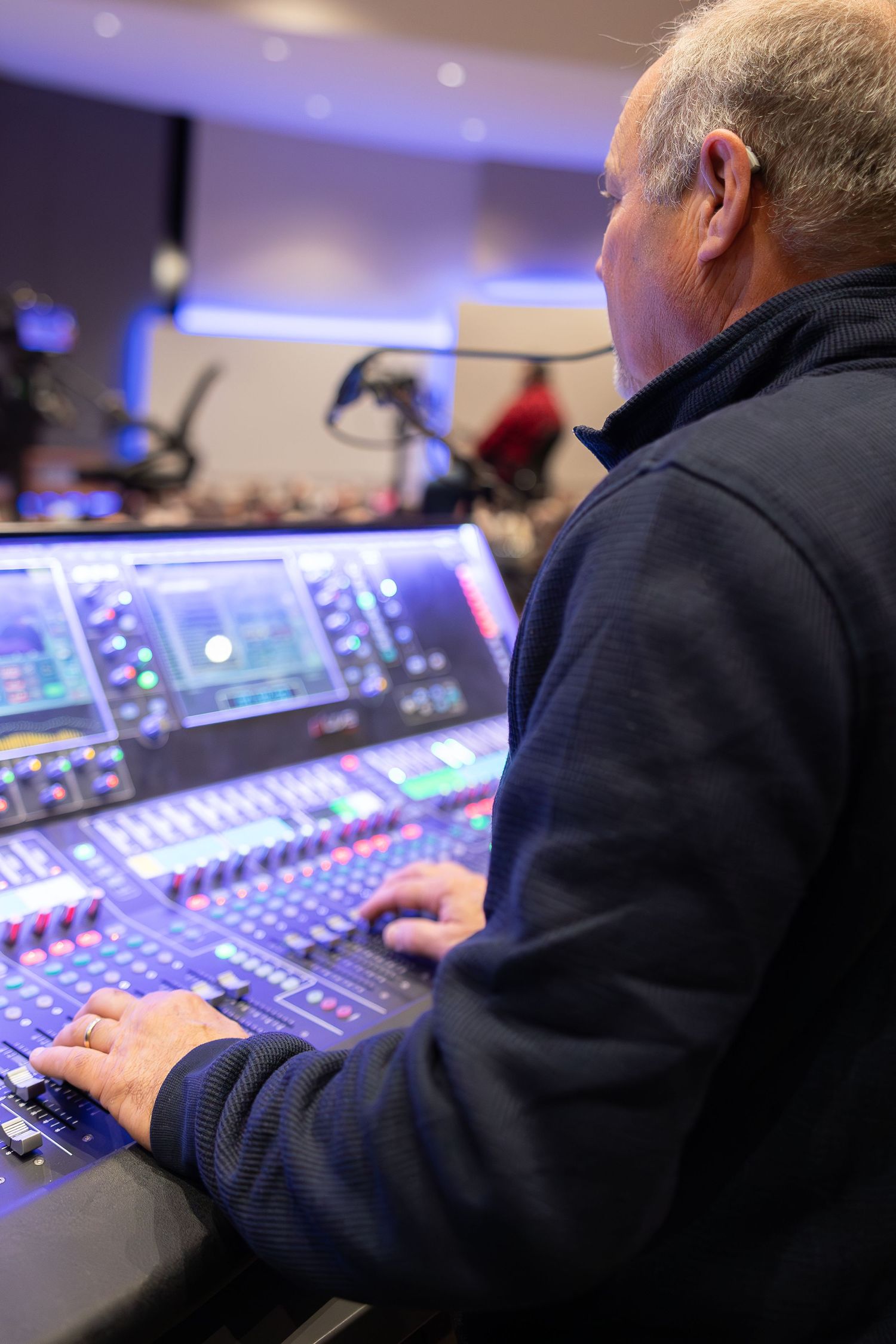 Audio engineer adjusting controls on a professional digital mixing console.
