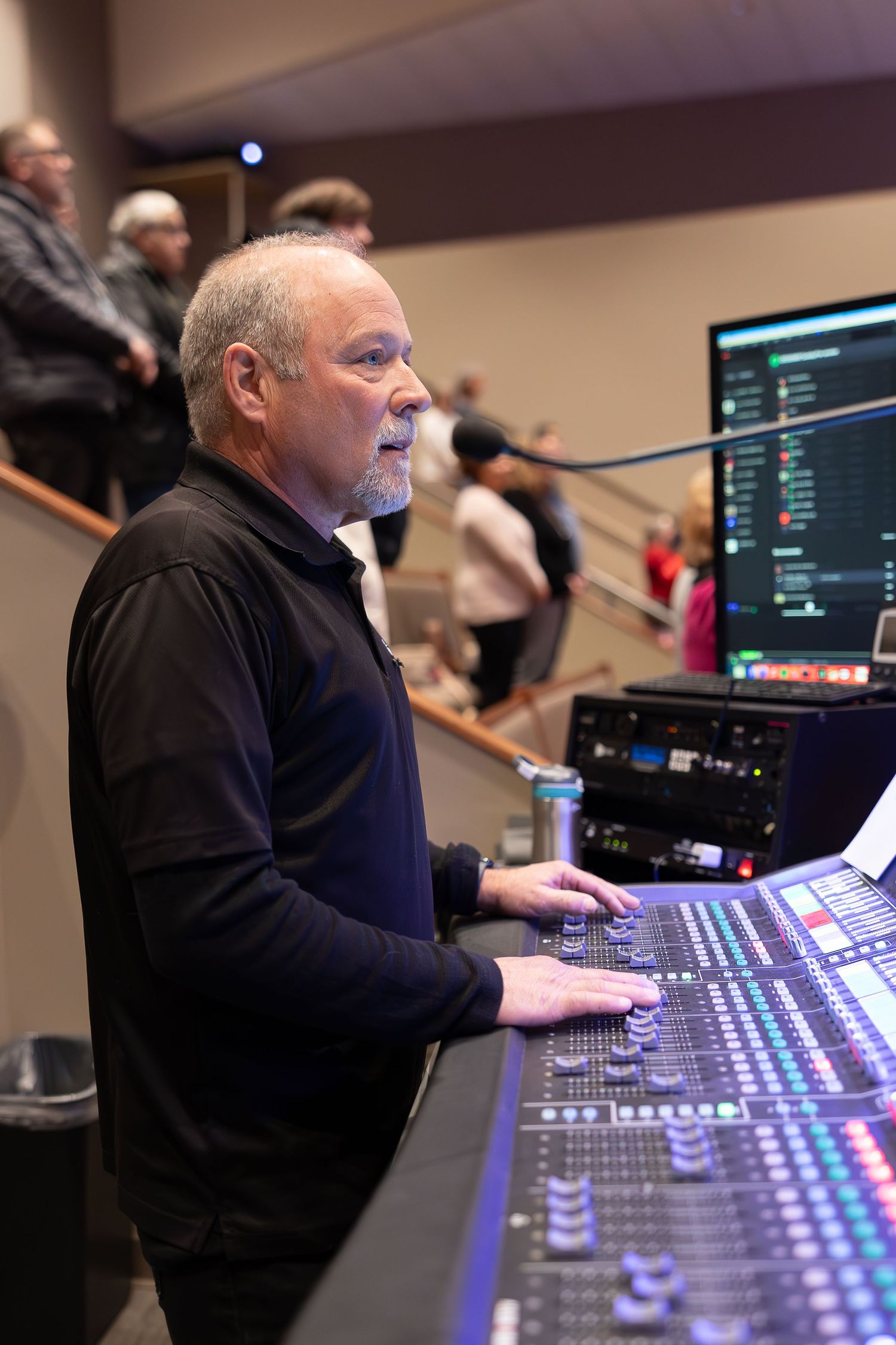 Sound engineer operating digital mixing console at live event.