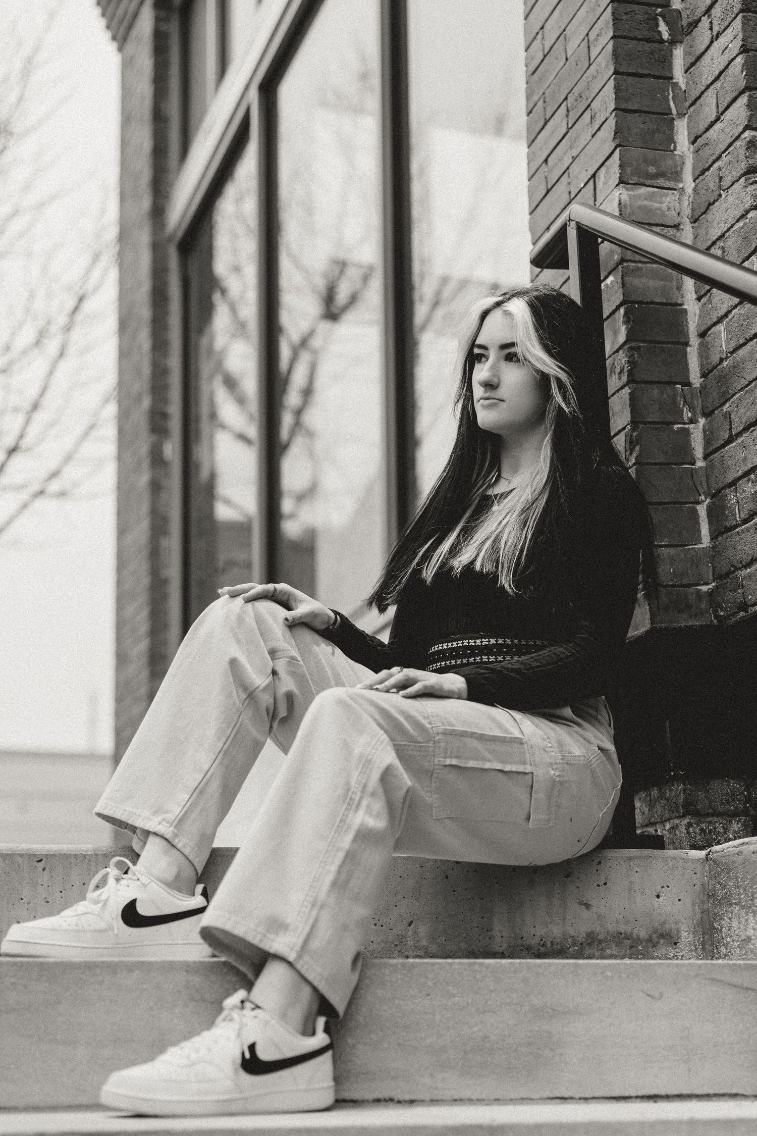 A casual portrait on concrete steps featuring relaxed denim and Nike sneakers.