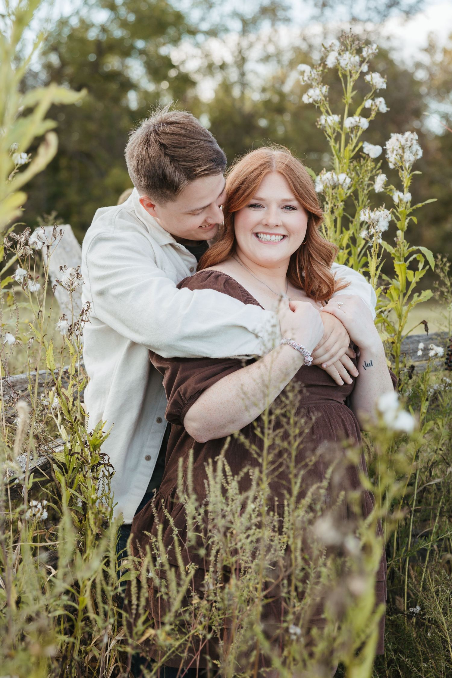 A romantic embrace in a wildflower meadow with golden afternoon light filtering through.