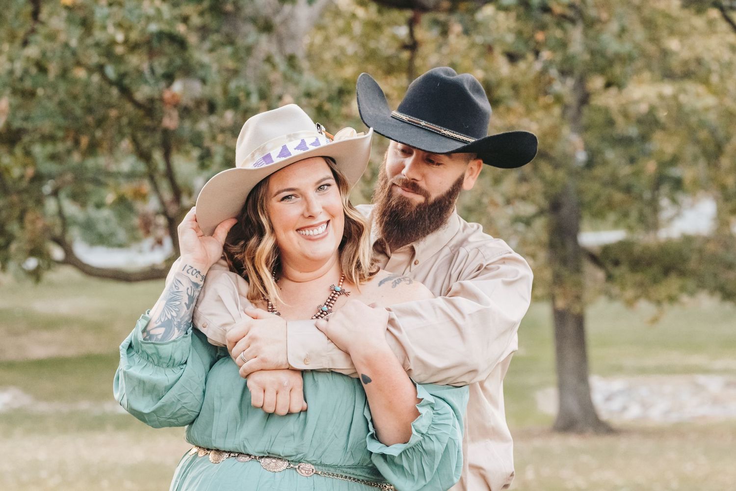 Couple in cowboy hats share an intimate moment while posing for outdoor photos.