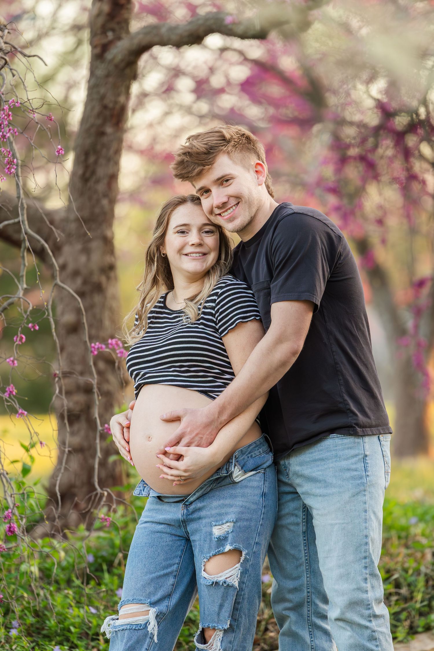 A springtime maternity photoshoot with blooming trees in the background.