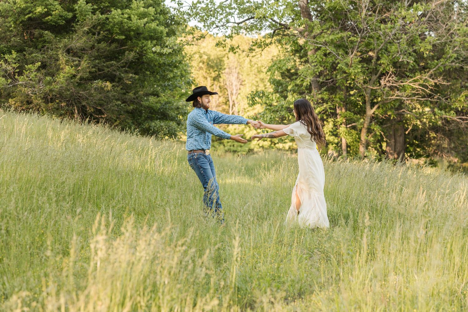 People in a field during golden hour with sunlight filtering through trees and tall grass.