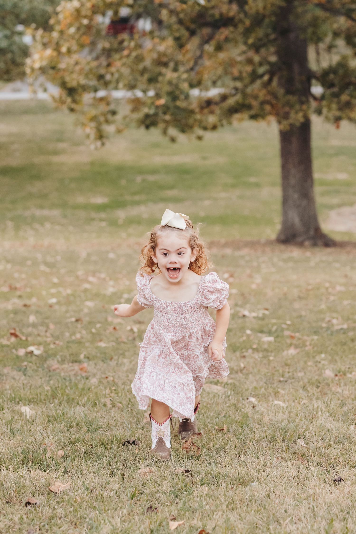 Young child in pink dress runs joyfully through an autumn field.