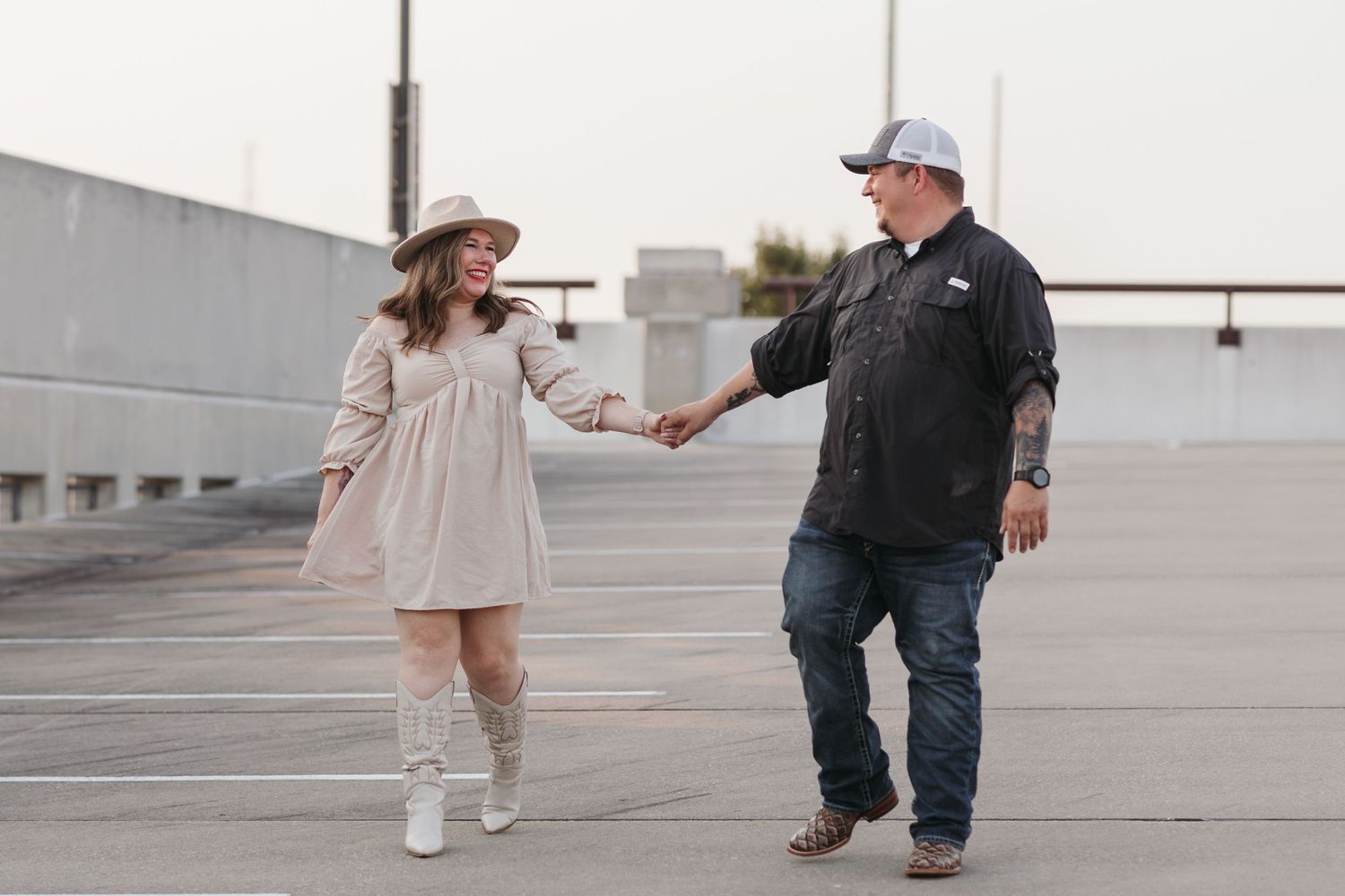 Two people share a playful moment walking together in an urban parking structure.
