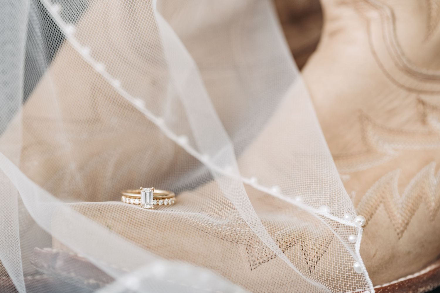 Diamond engagement ring resting on delicate white wedding veil fabric.