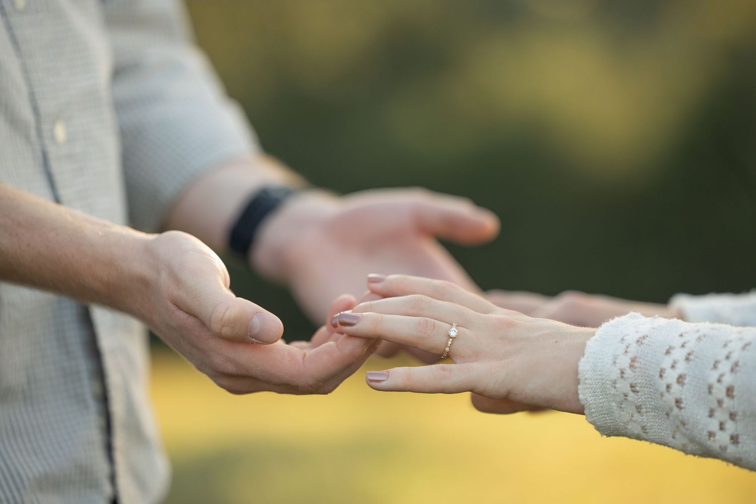Close up of hands during a romantic proposal moment in soft natural lighting.