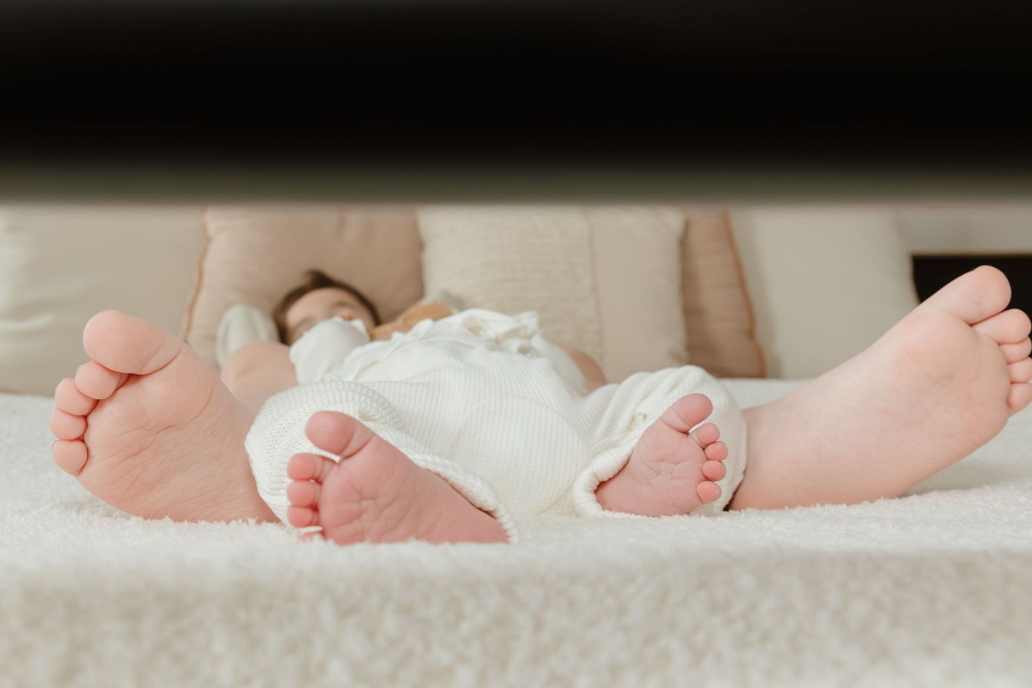 Close-up view of two pairs of tiny baby feet resting on white fabric.