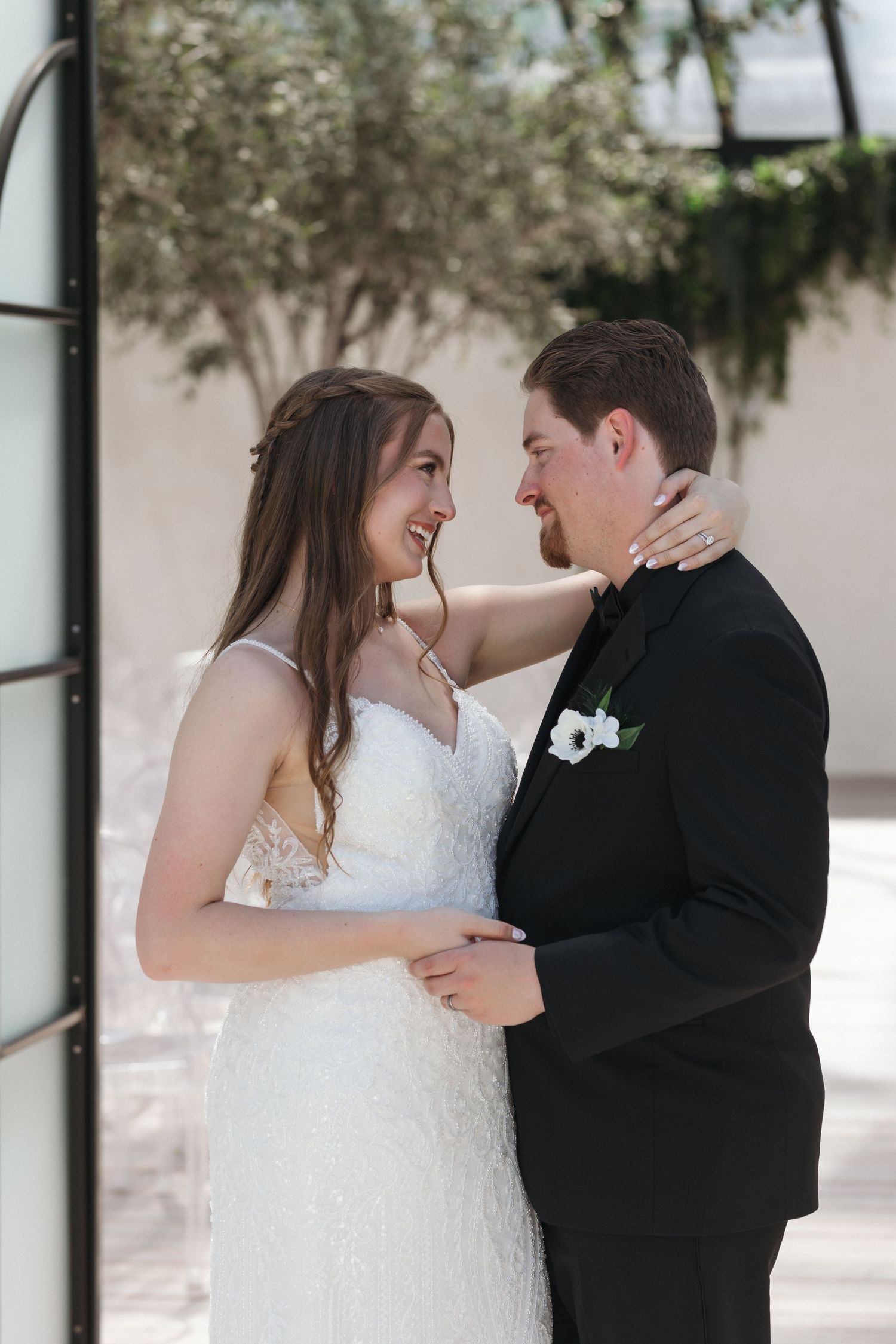 An intimate moment between newlyweds as they embrace and smile at each other outdoors.