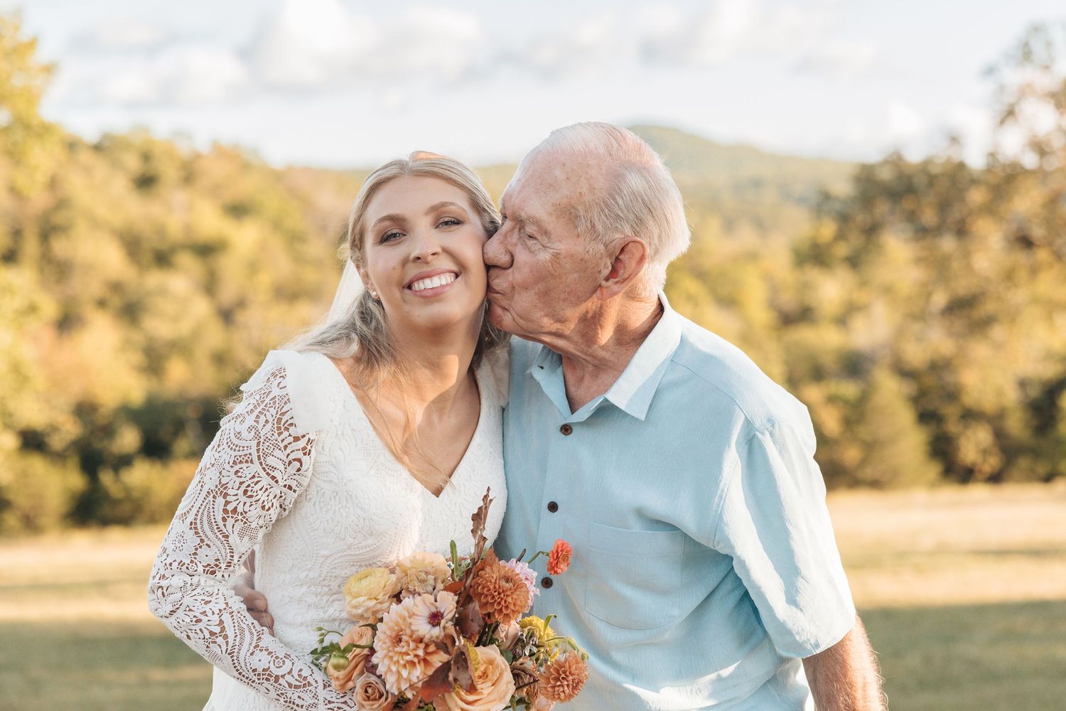 A tender moment between a couple in wedding attire sharing laughter in a golden outdoor setting.