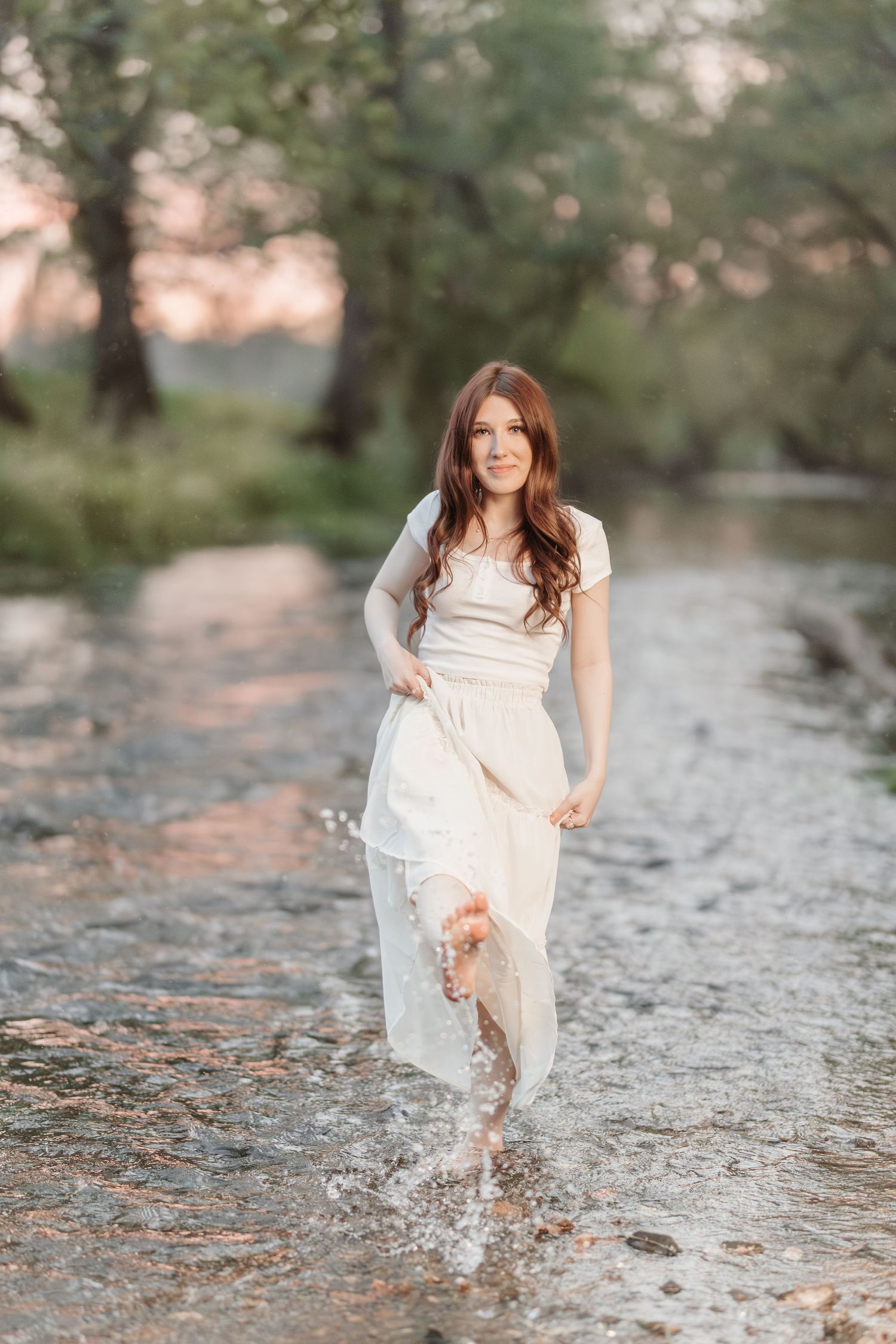 A whimsical photo of someone splashing in shallow water while wearing a flowing white dress.