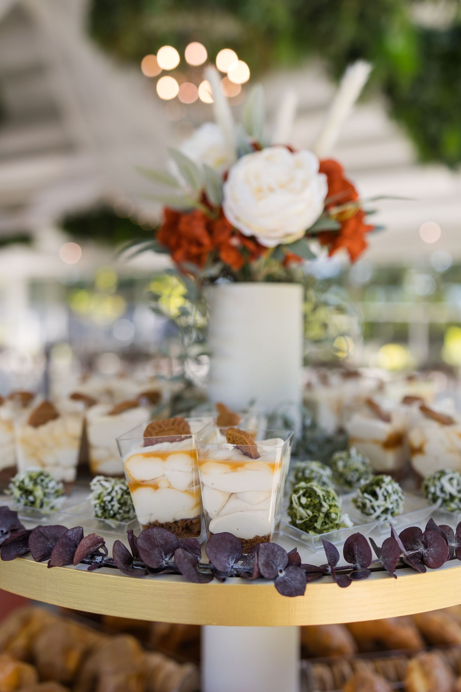 Elegant dessert table display with caramel biscoff cups and floral arrangement at a wedding reception.