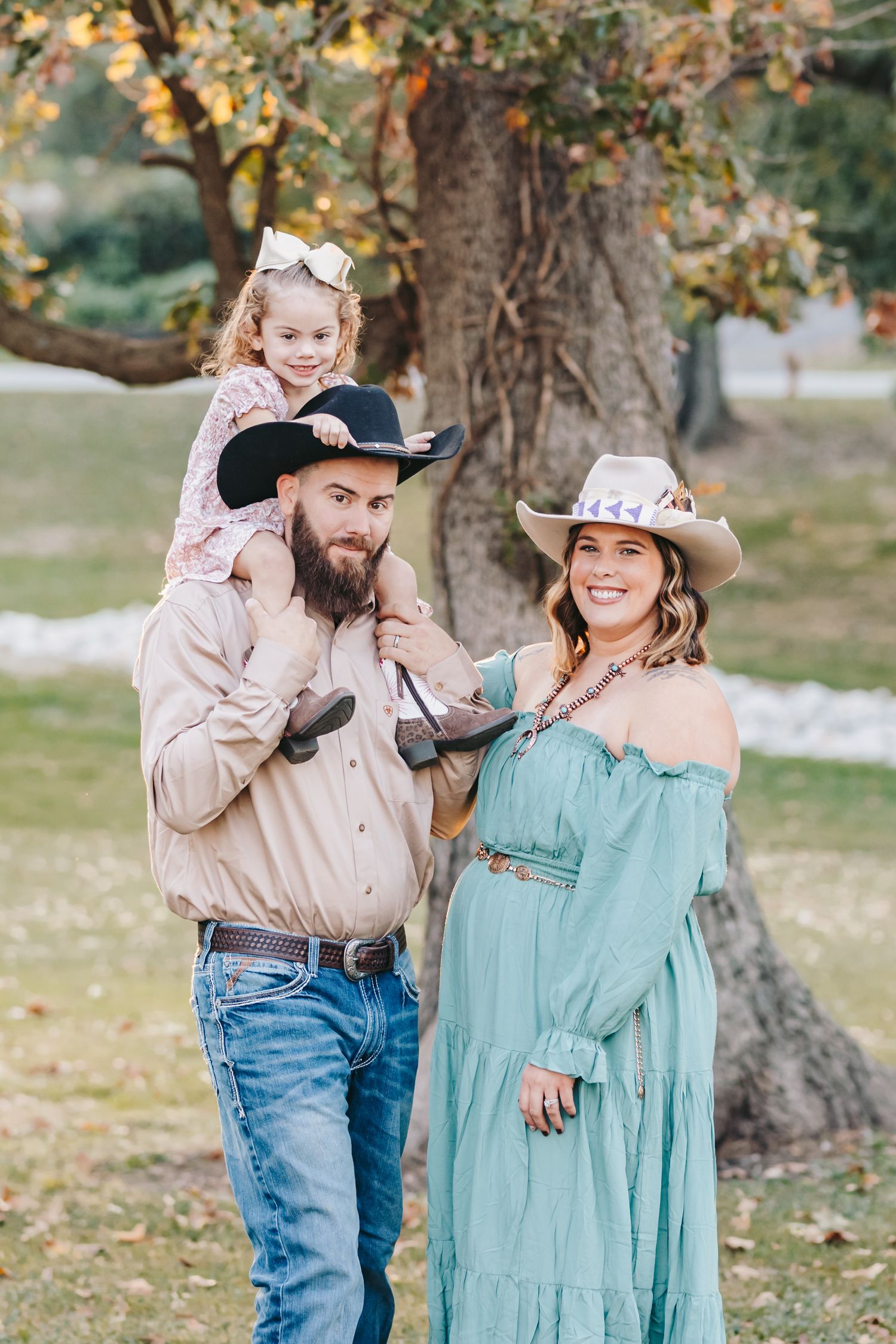 Casual western family portrait beneath autumn trees with rustic charm.