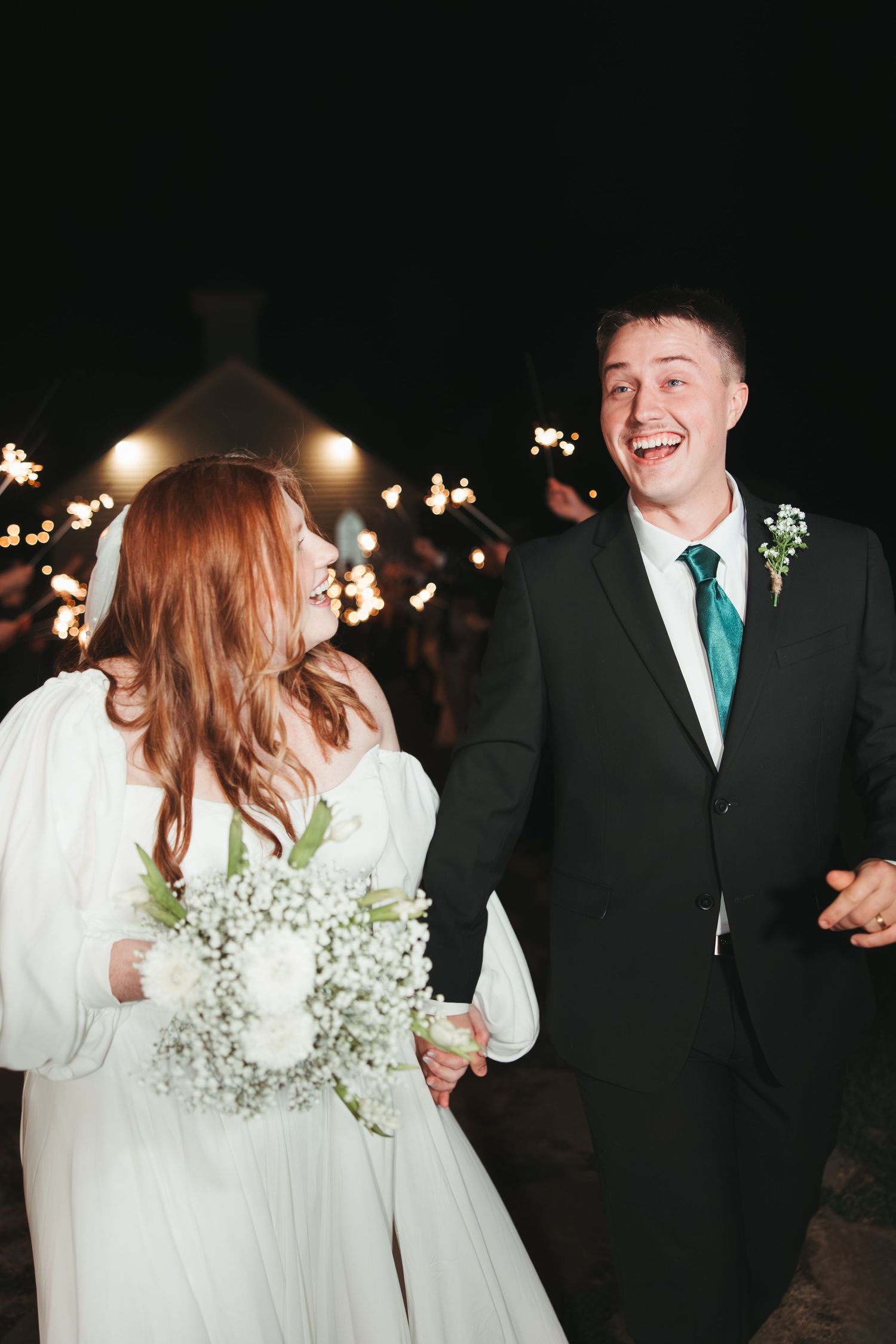 Candid moment of newlyweds laughing during sparkler exit.