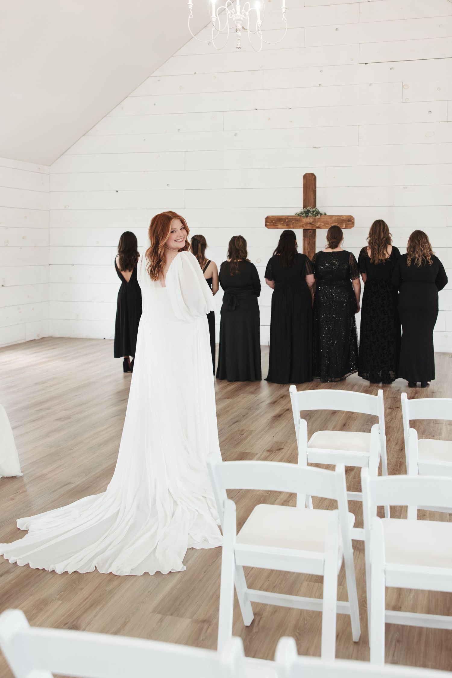 Wedding ceremony in white chapel with choir in black robes and wooden cross.