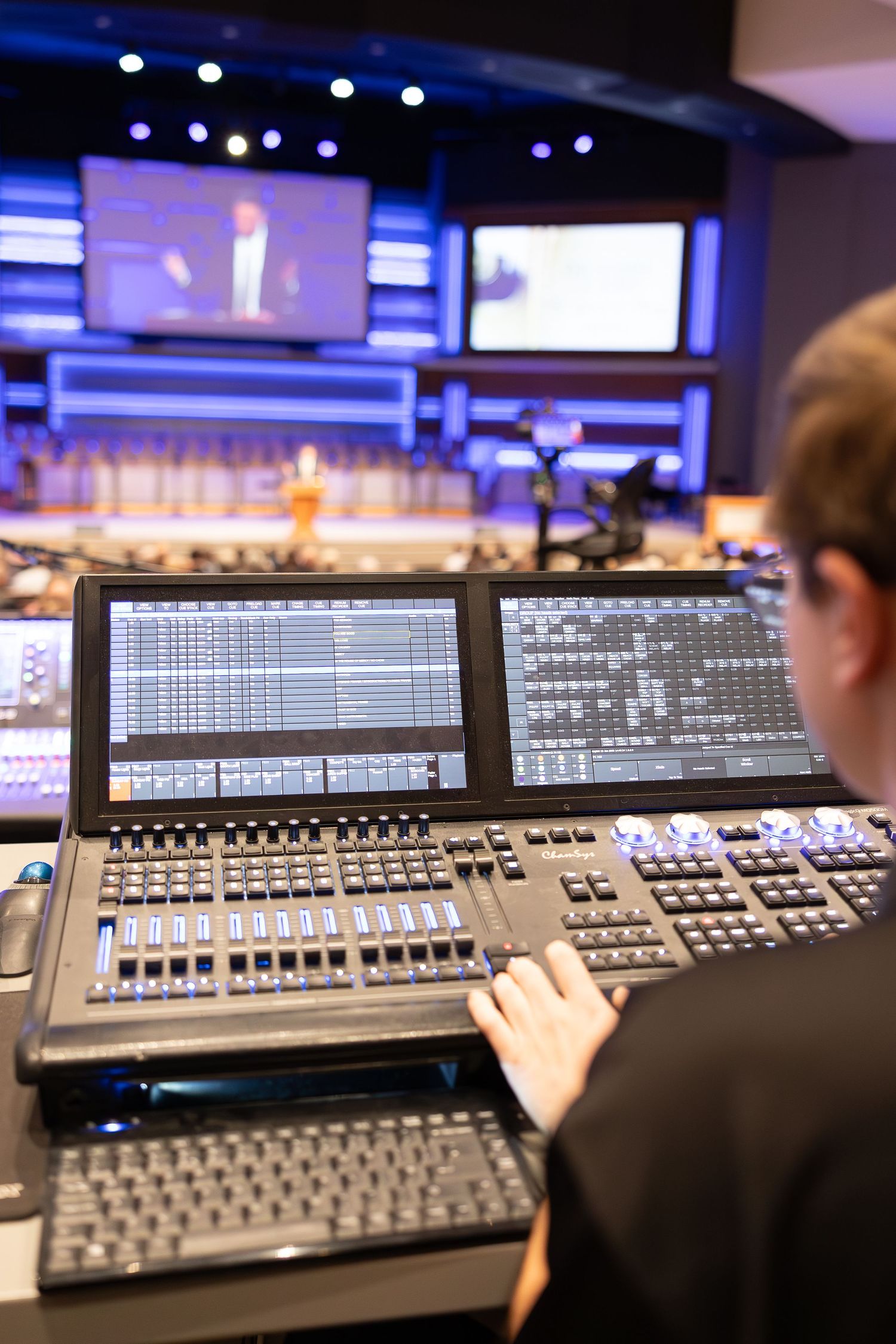 Sound engineer working at a professional digital mixing console with multiple screens.