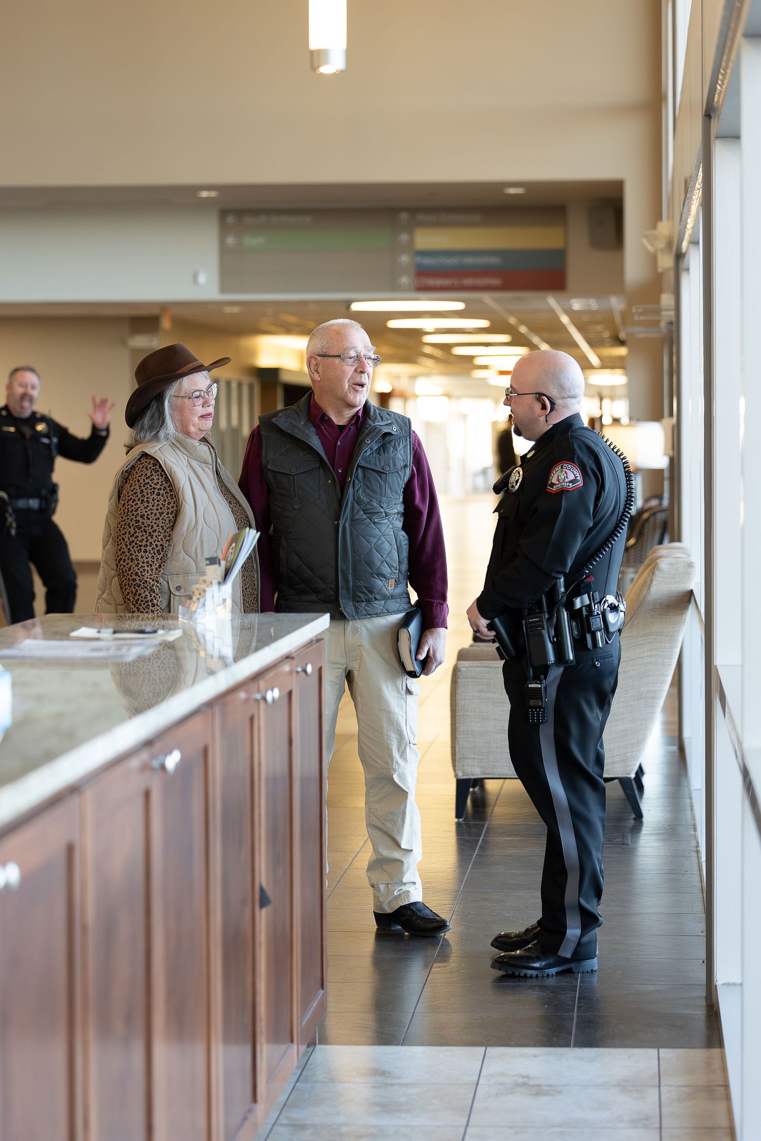 Security personnel and visitors having a conversation in a modern building hallway.