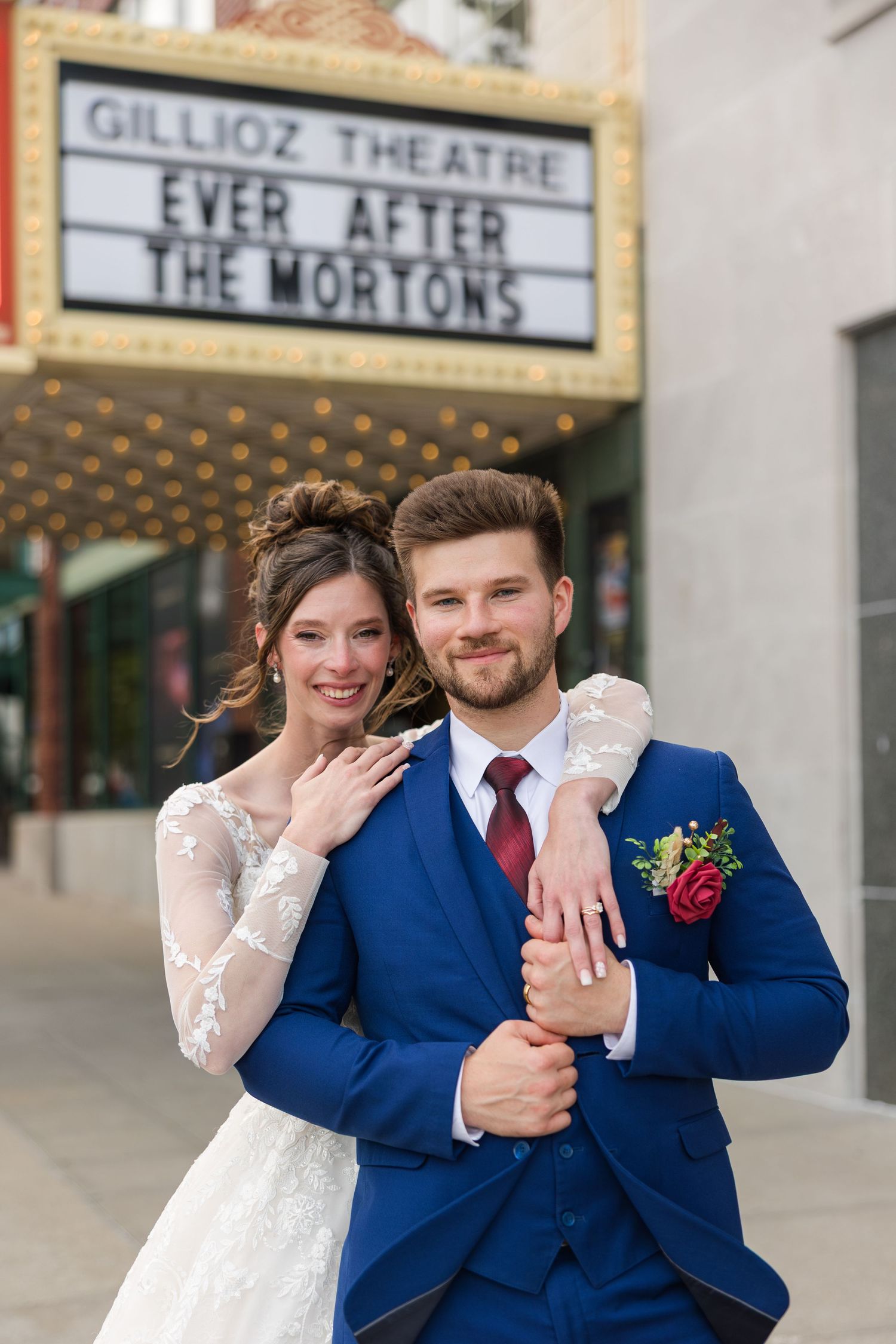 Bride and groom pose in front of the Gillioz Theatre marquee reading Ever After The Mortons on their wedding day.