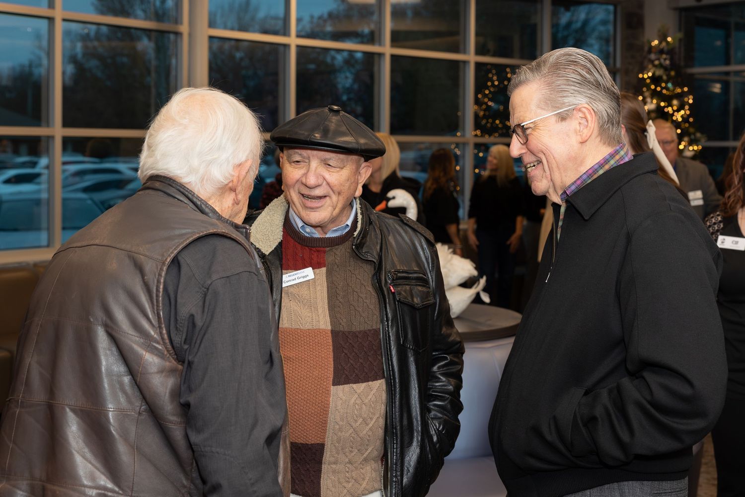 Three guests conversing during an evening social gathering.