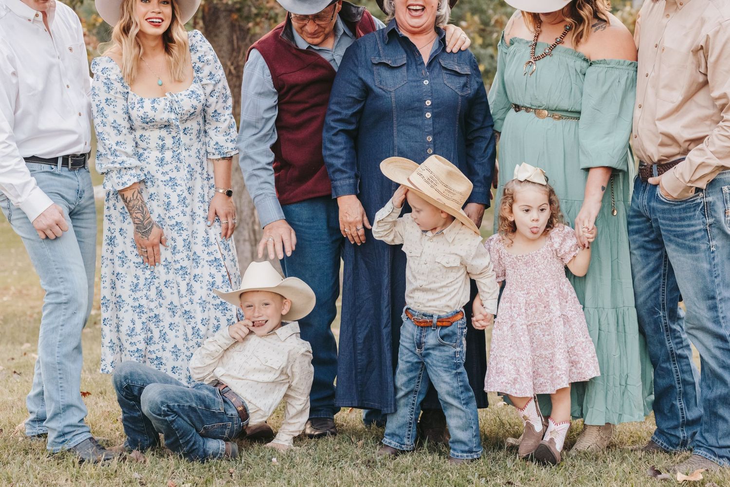 Family gathering photo with western-style clothing and cowboy hats in golden evening light.