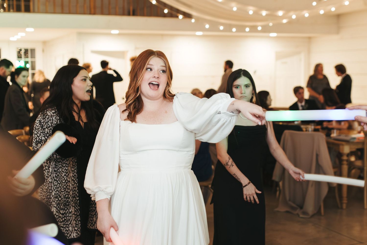 Wedding celebration on dance floor with white dress and string lights creating festive atmosphere.