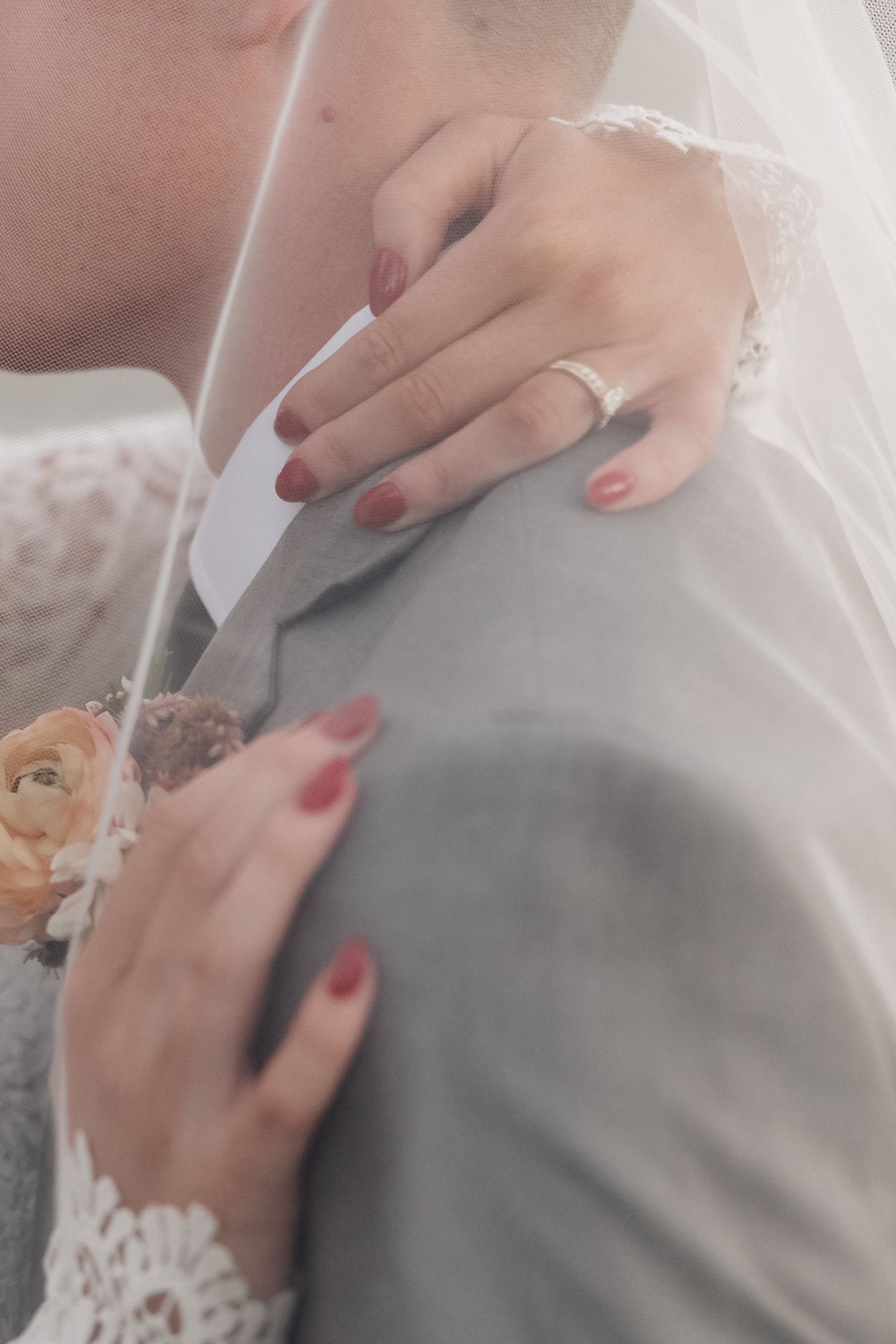 Close-up detail shot of wedding rings and lace sleeve details during intimate moment.
