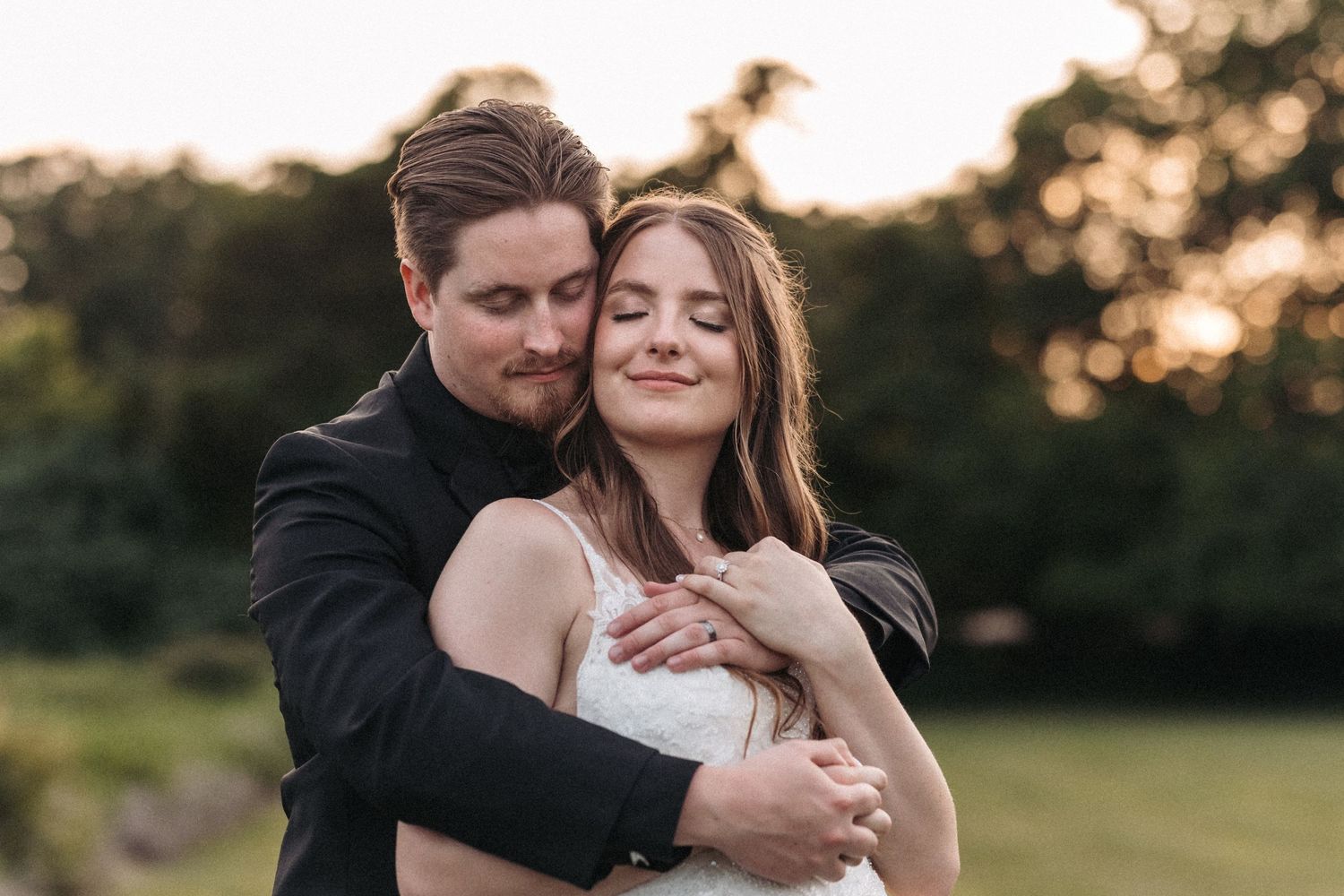 A romantic embrace between newlyweds in a sunlit meadow during golden hour.