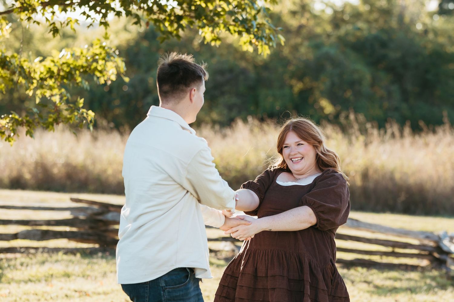 Two people share a joyful dance moment together in a scenic outdoor setting during golden hour.