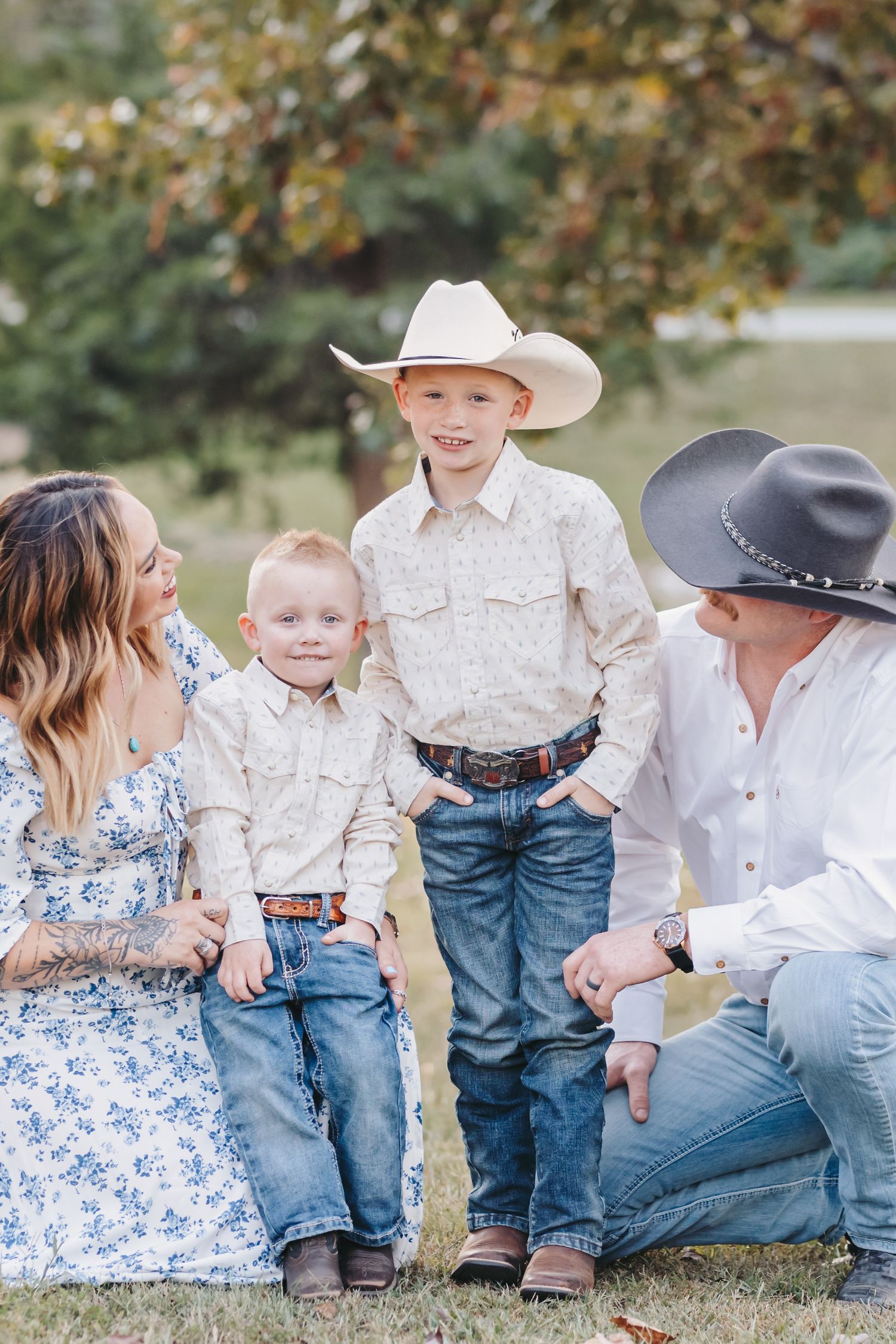 Family in coordinated western wear shares joyful moment during outdoor photoshoot.