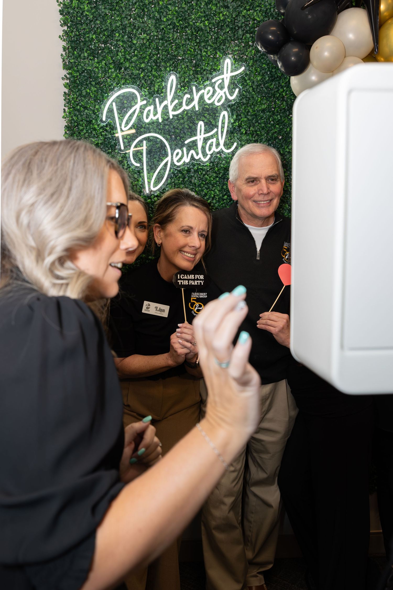 Staff members gather for photos at a Parkcrest Dental event with a neon sign backdrop.