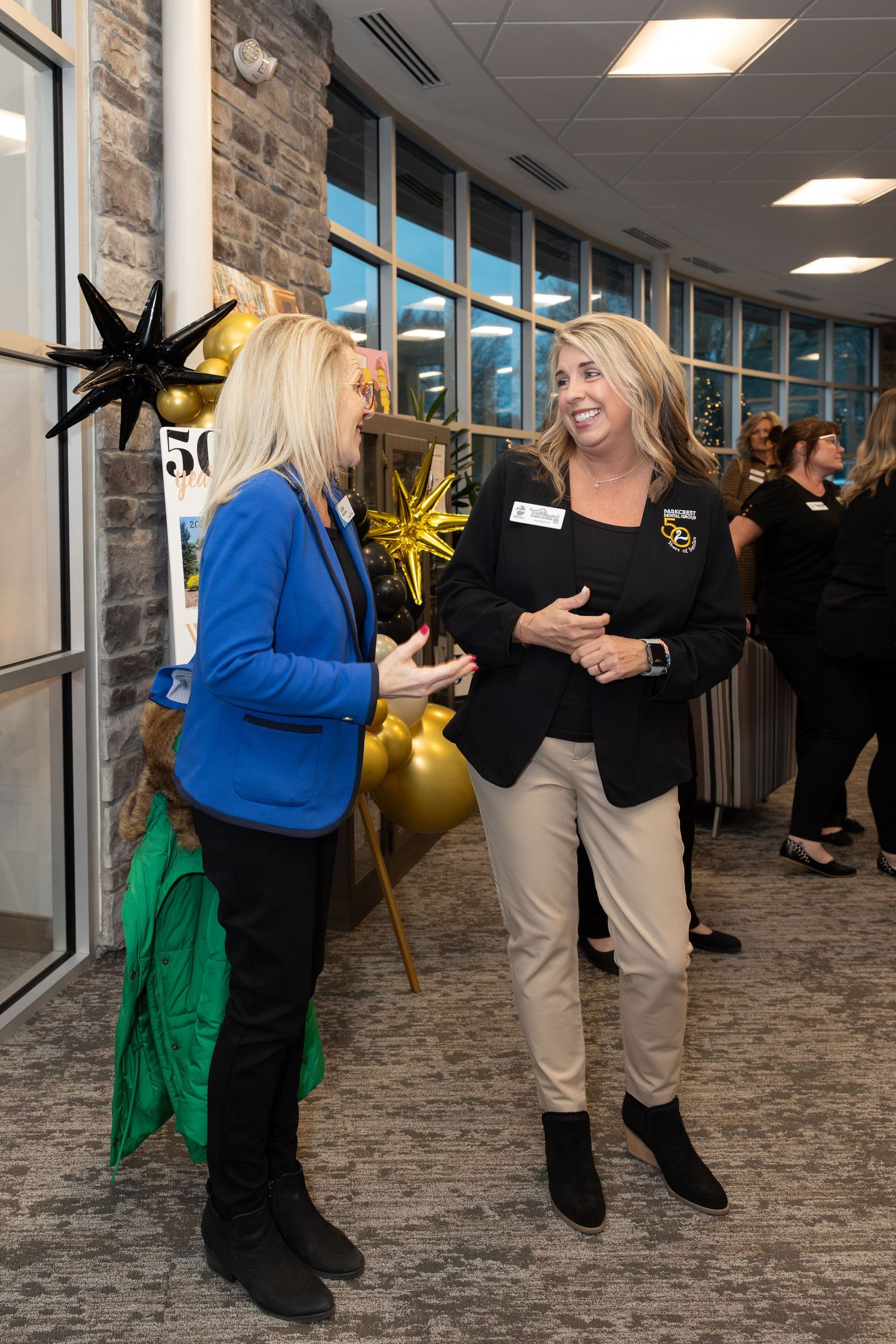 Two people having an animated conversation near decorative star ornaments.