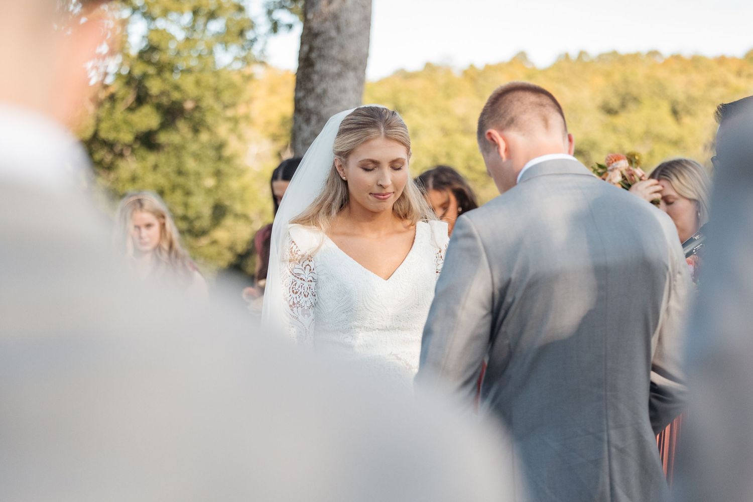 An intimate wedding ceremony moment captured with guests and a wooden cross in the background.