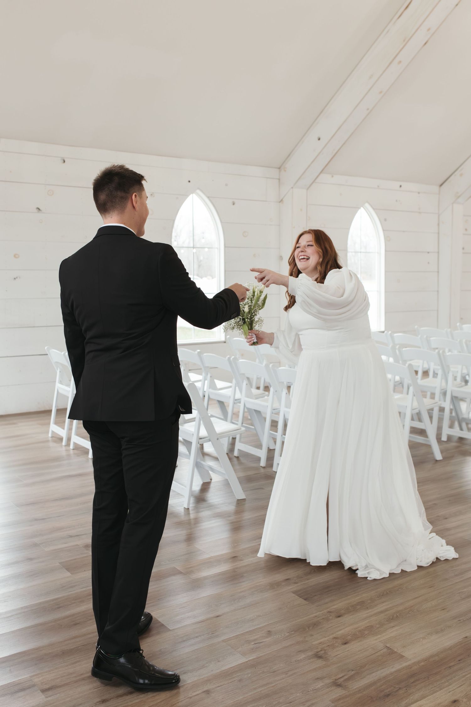 Joyful moment between couple in wedding attire inside white chapel.