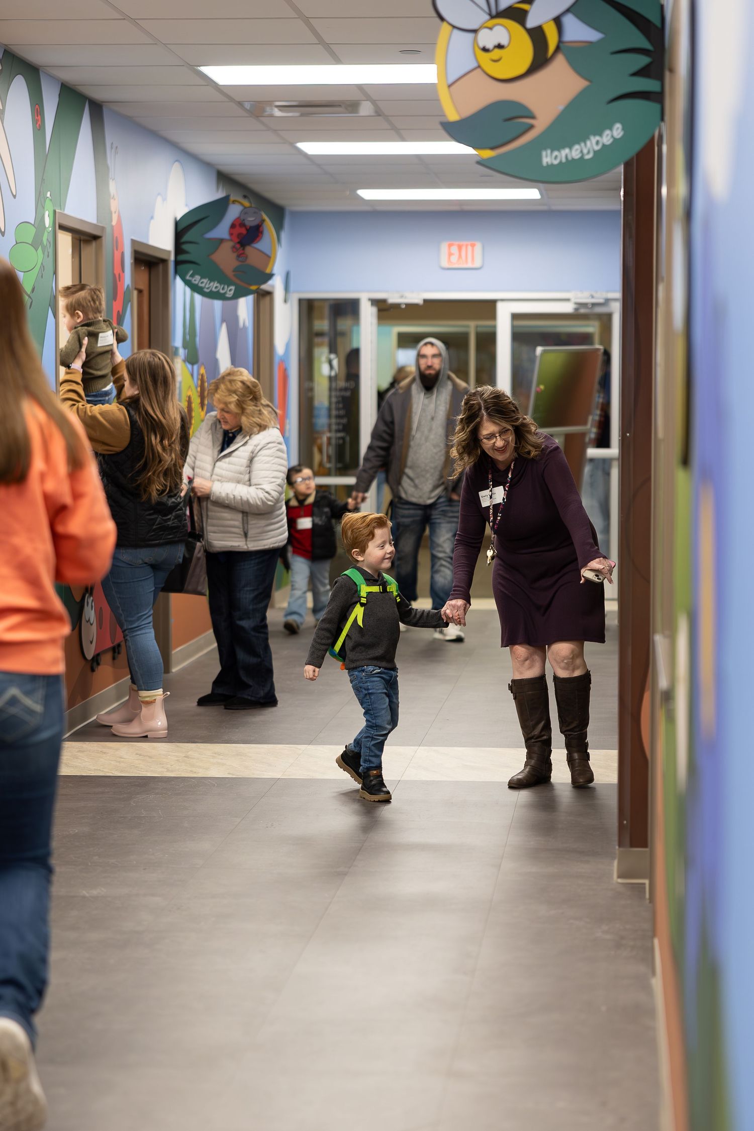 People walking through a cheerfully decorated hallway with cartoon bee decorations overhead.