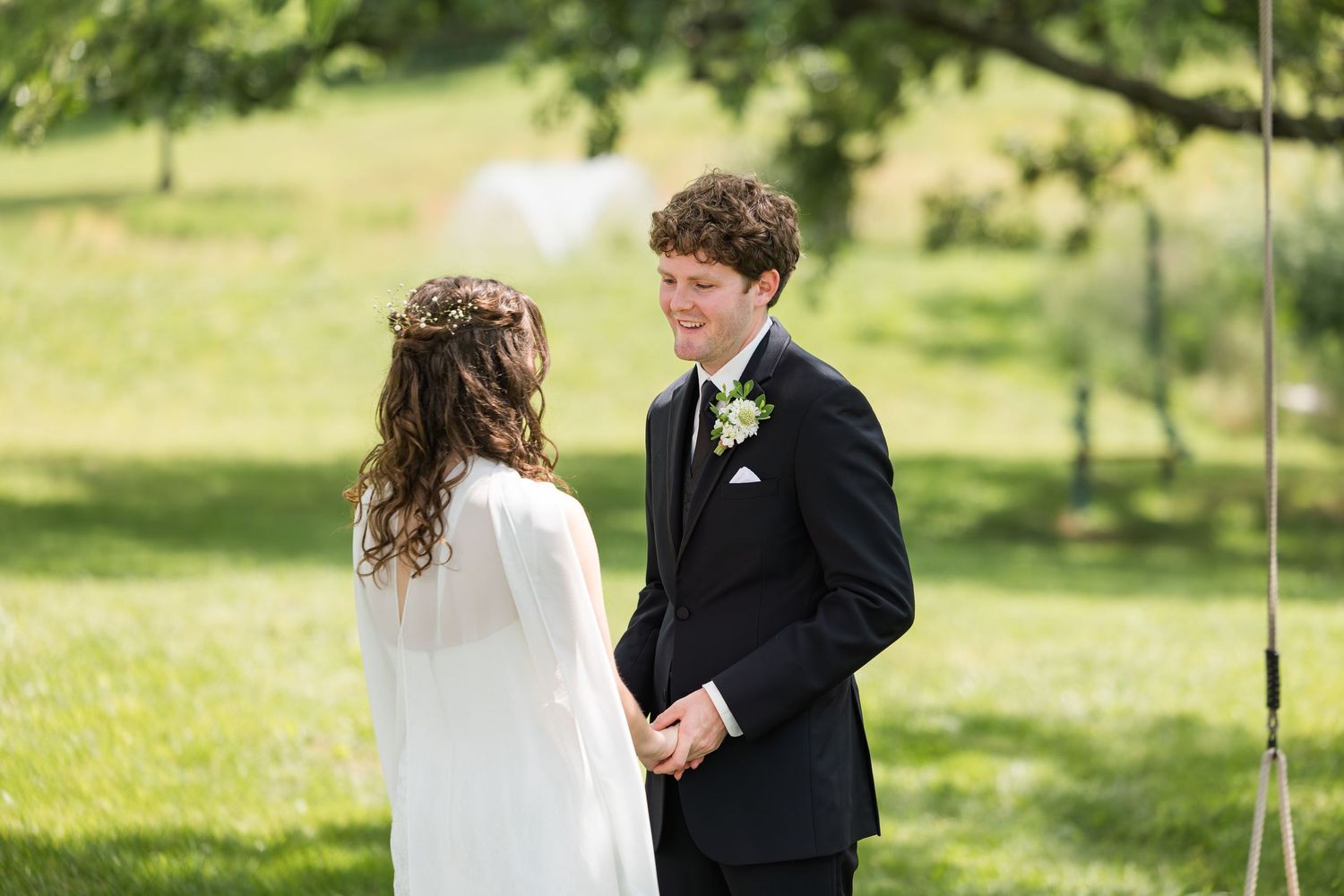 Bride and groom exchange vows outdoors in lush green garden wedding ceremony setting.