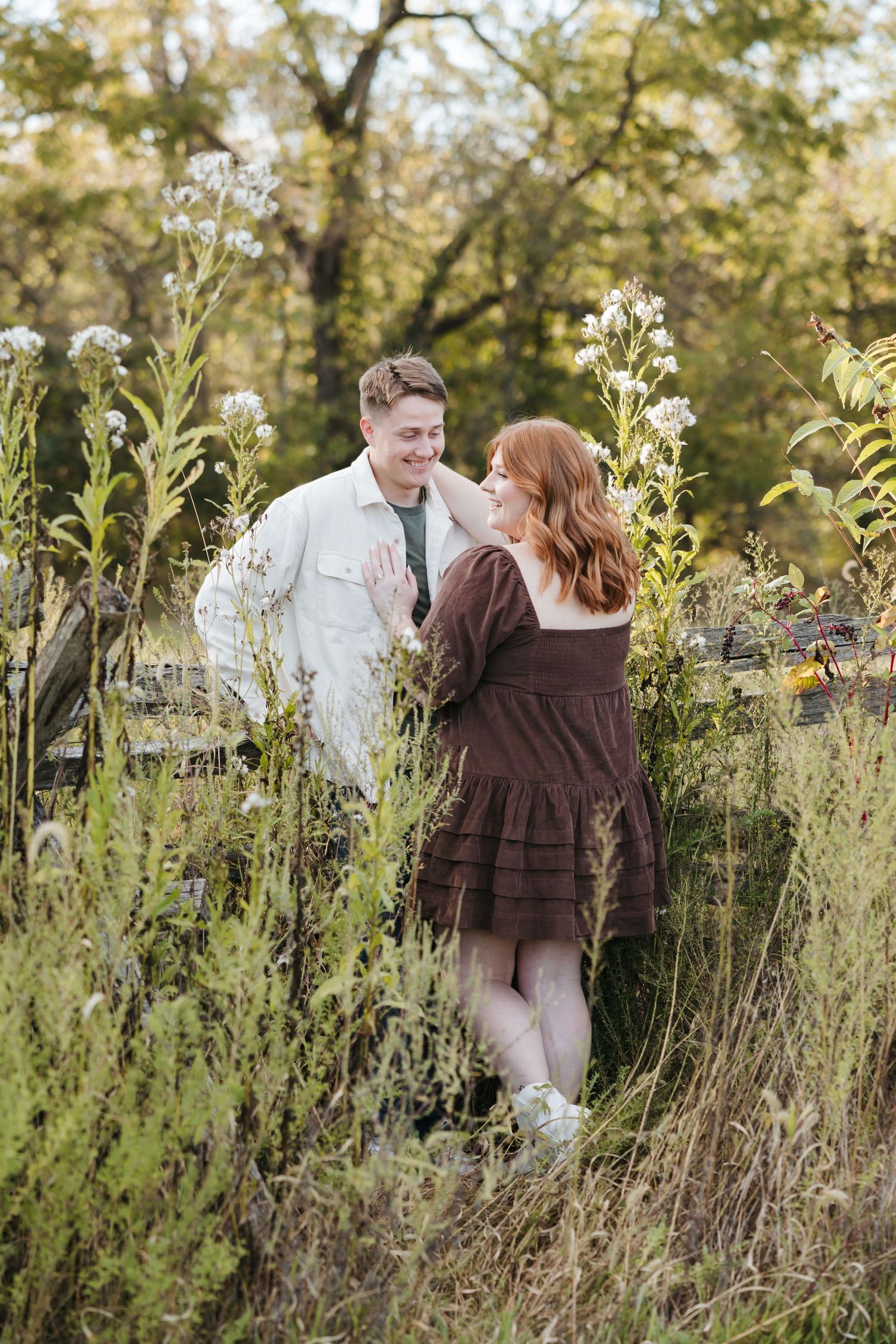 Romantic couple sharing intimate moment among tall wildflowers in natural setting.