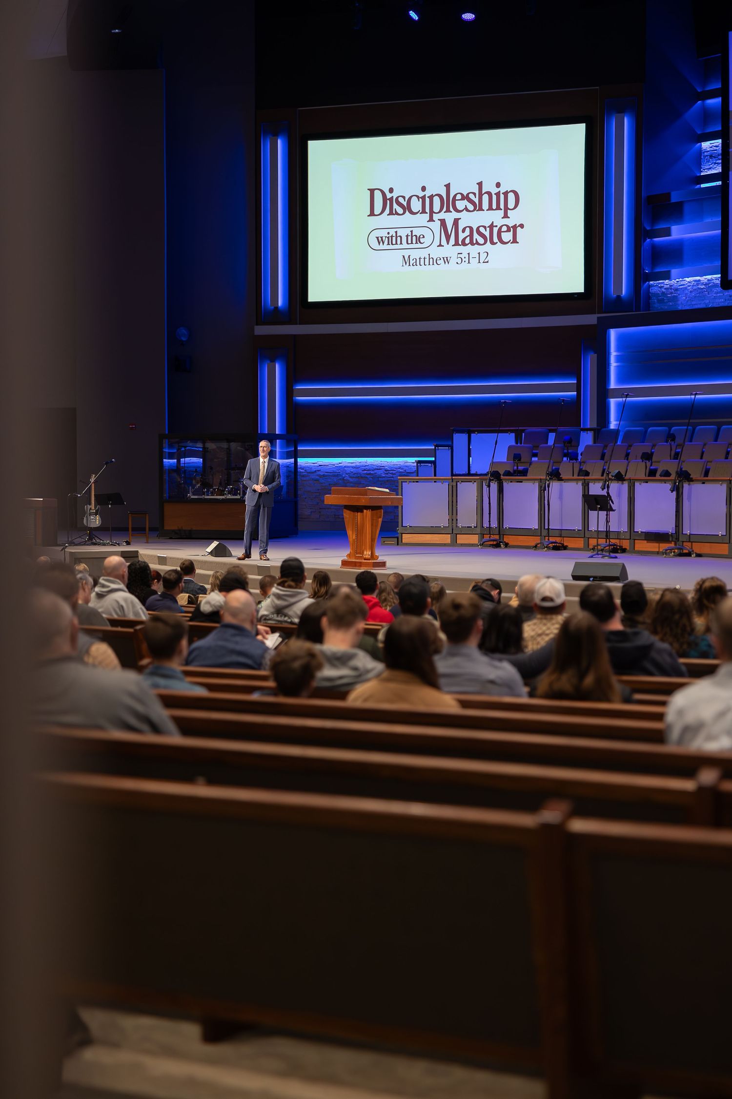 A church sanctuary during a presentation about discipleship with rows of wooden pews.