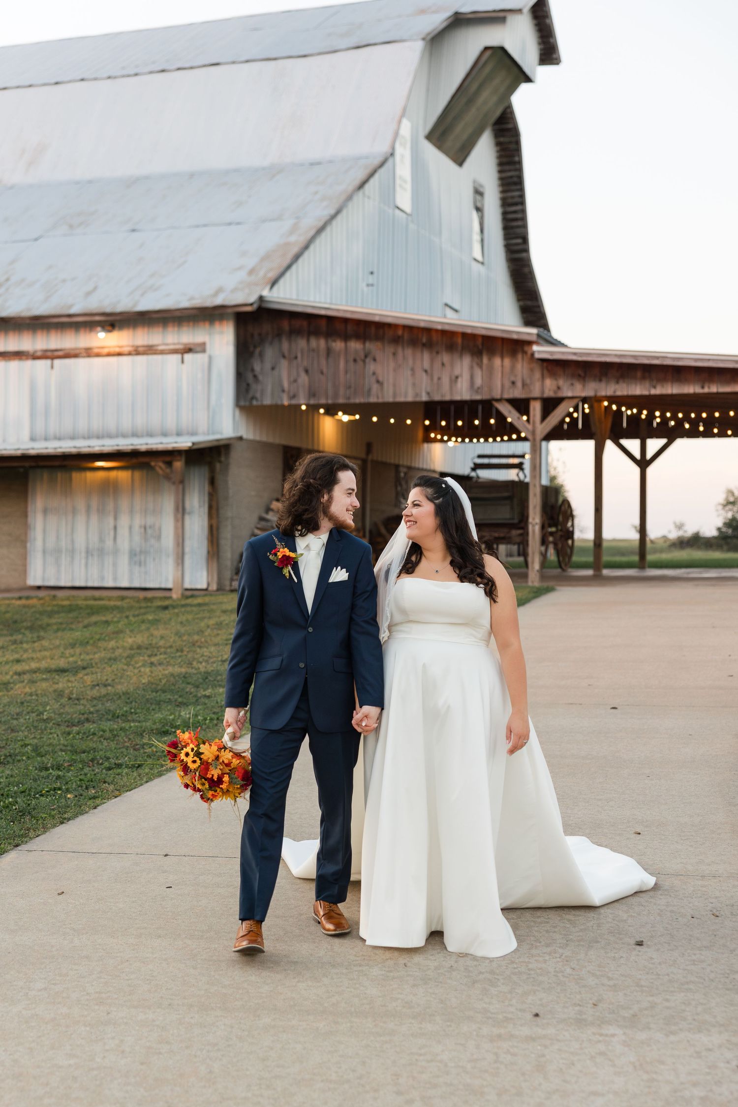 A rustic barn wedding venue with string lights and a couple sharing intimate moments at sunset.