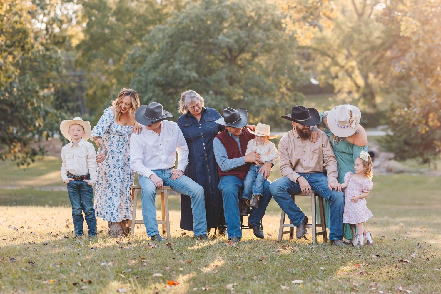 A casual family gathering outdoors with everyone dressed in western wear and cowboy hats.