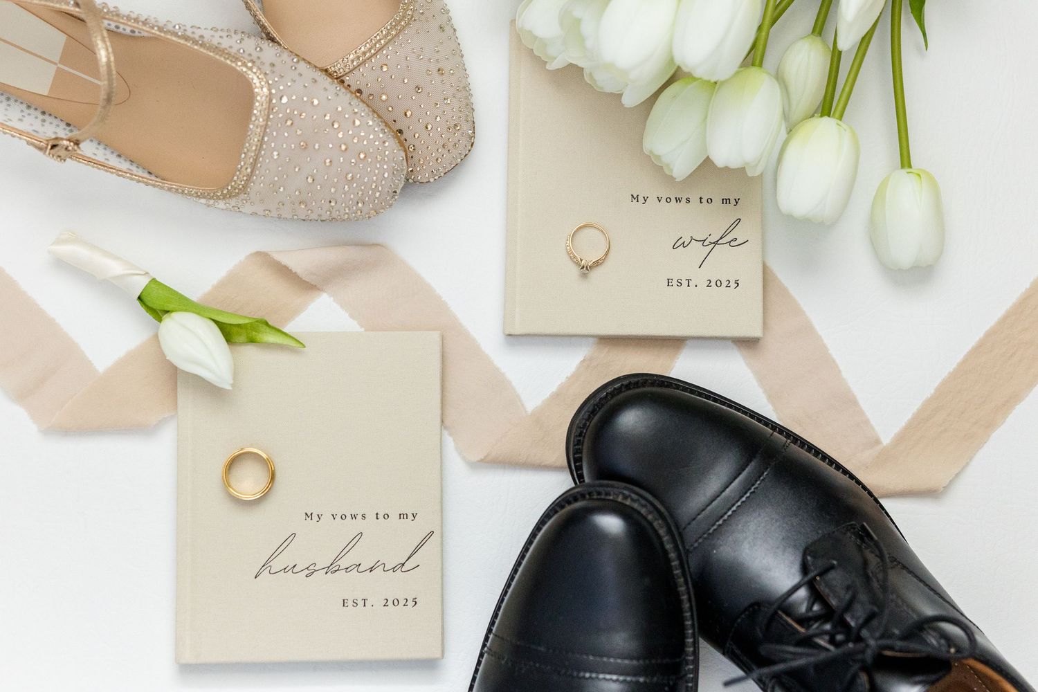 Neutral beige bridal accessories with wedding shoes, rings, and white tulips arranged on a light background.