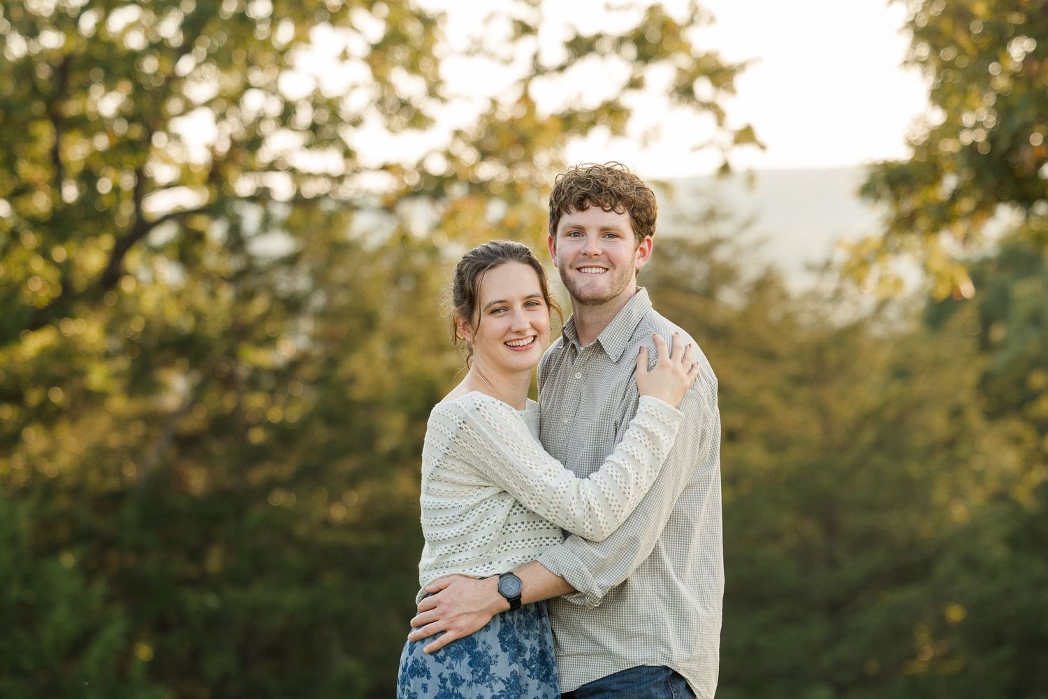 Couple sharing affectionate moments in a sunlit outdoor setting during a photo session.